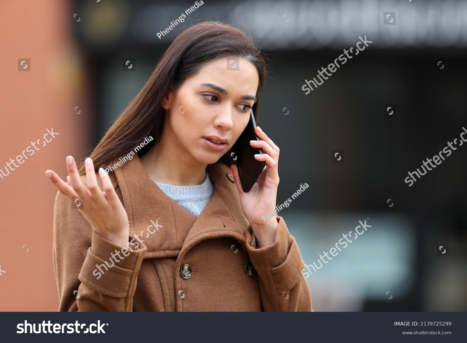 Angry woman in the street talking on mobile phone complaining #2139725299