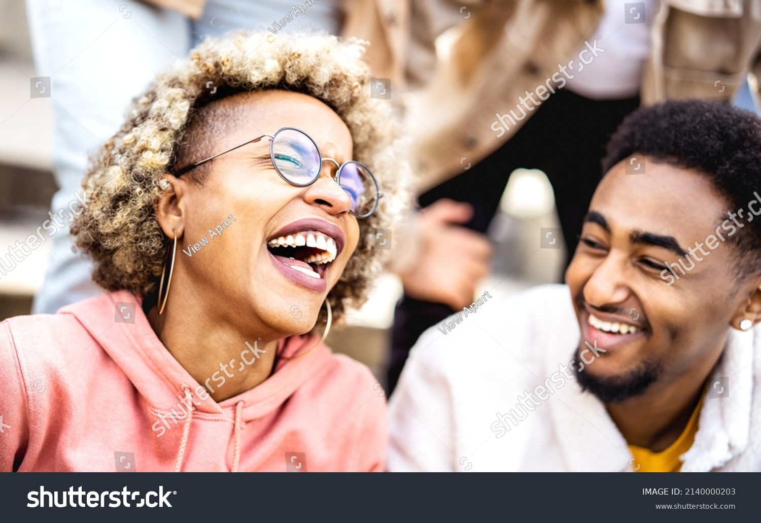 Multicultural couple on genuine laughter - Life style concept with happy multiracial friends having fun together out side - Trendy college students enjoying break time at campus - Warm vivid filter #2140000203