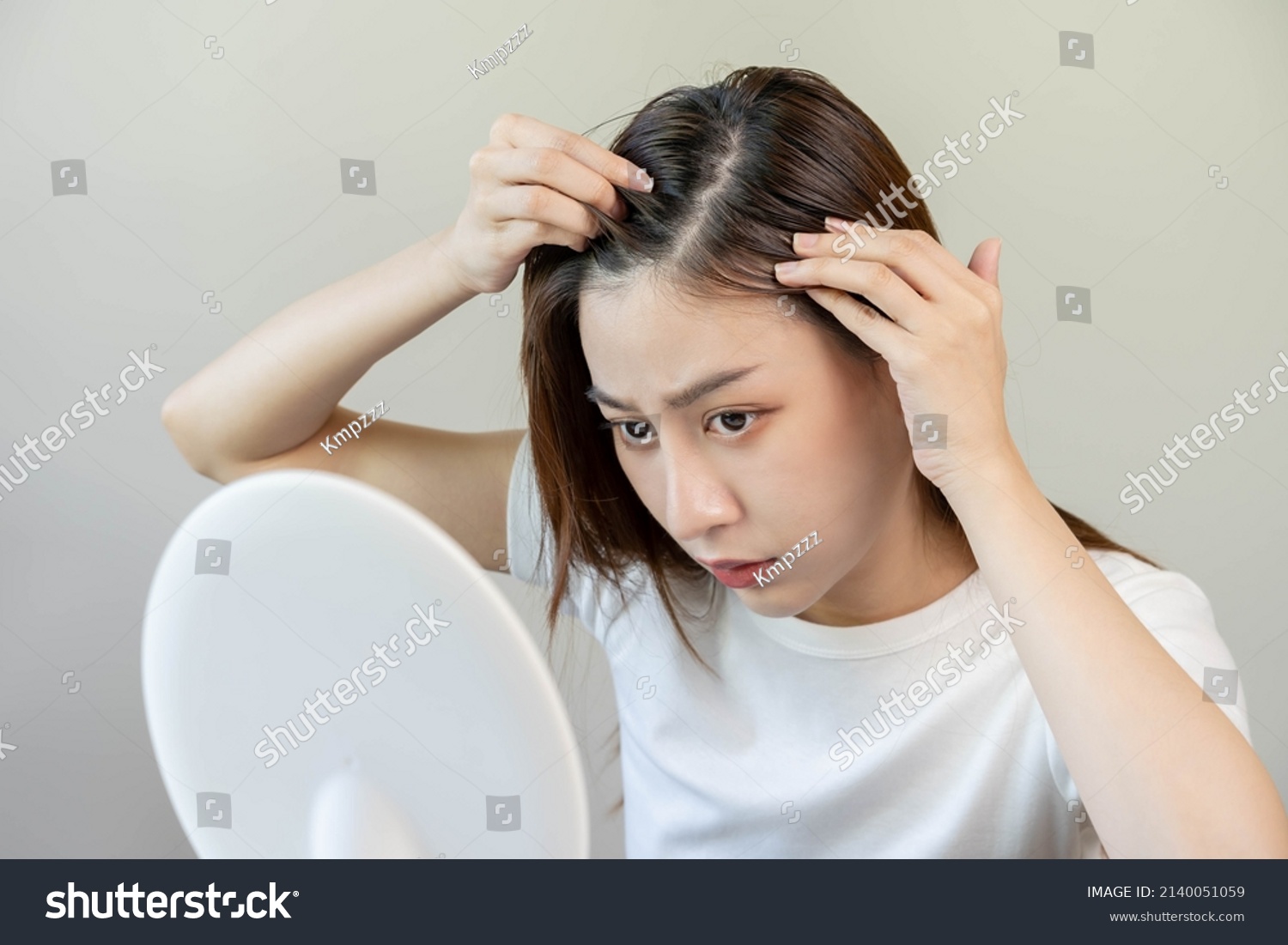 Damaged Hair, face serious asian young woman worry looking at scalp in mirror, hand in break into front hair loss, thin problem symptom at home. Health care shampoo beauty, isolated on background. #2140051059