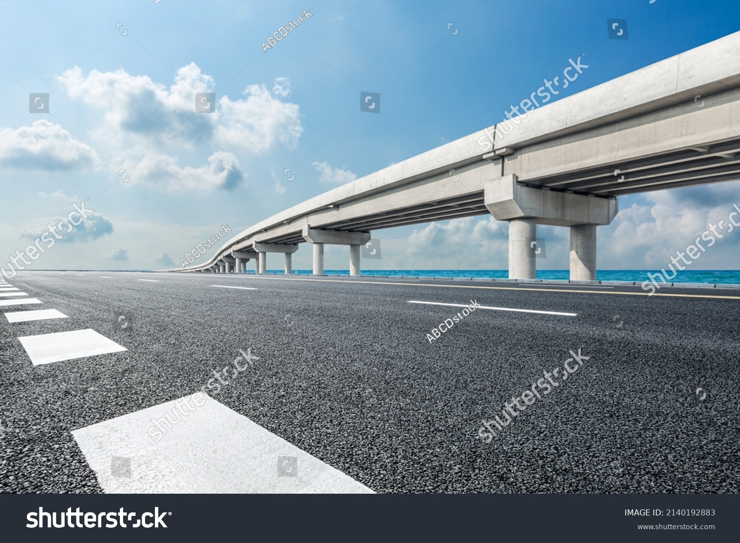 Empty asphalt road and river with bridge under blue sky #2140192883
