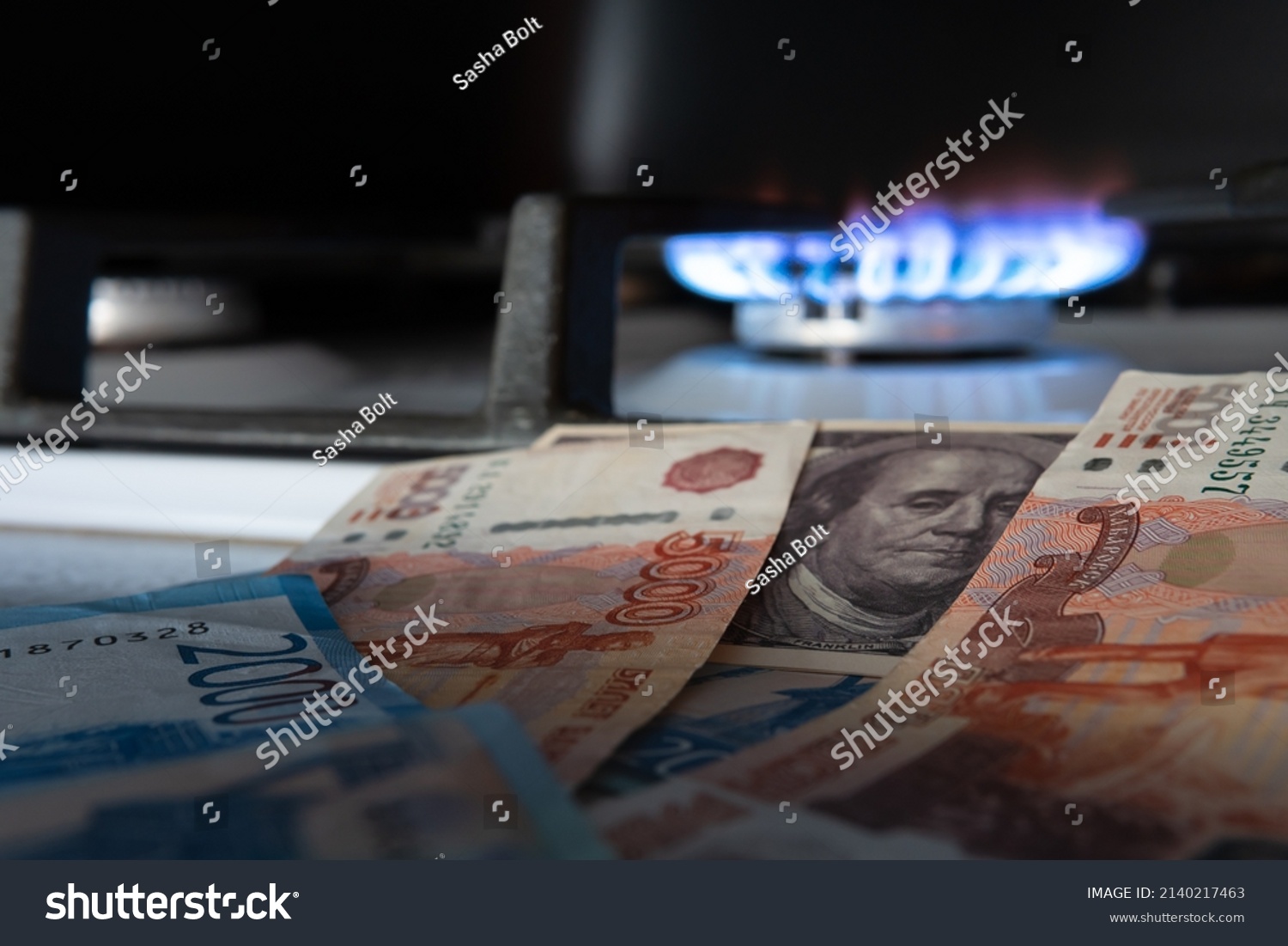 Russian currency on the background of the dollar and burning gas.The concept of gas and oil payment in Russian currency.Selective focus. #2140217463