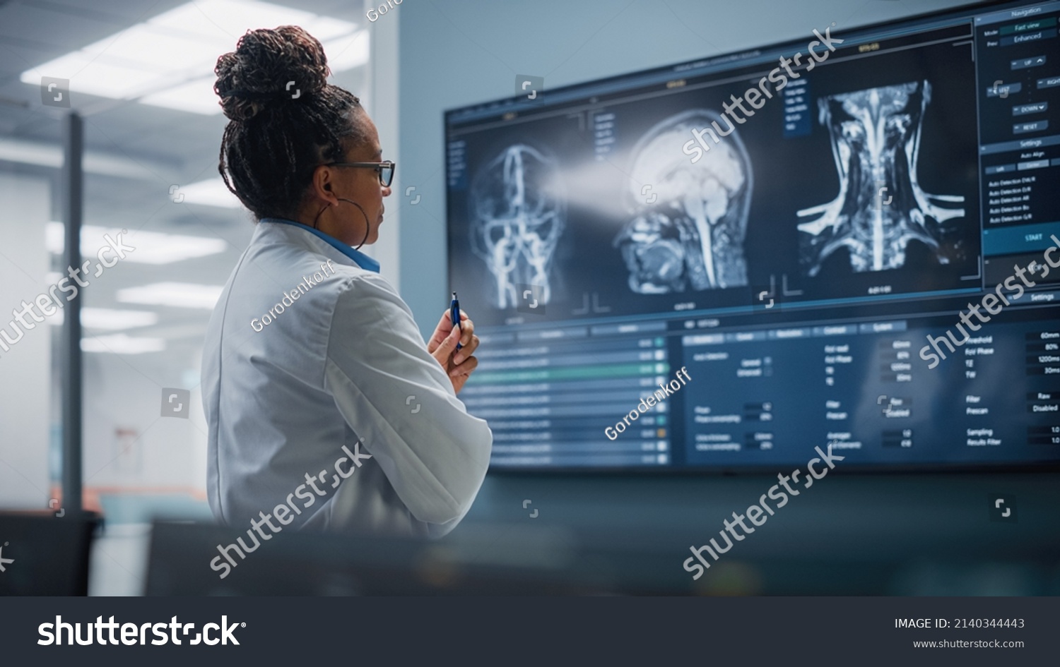 Medical Science Hospital: Confident Black Female Neurologist, Neuroscientist, Neurosurgeon, Looks at TV Screen with MRI Scan with Brain Images, Thinks about Sick Patient Treatment Method. Saving Lives #2140344443
