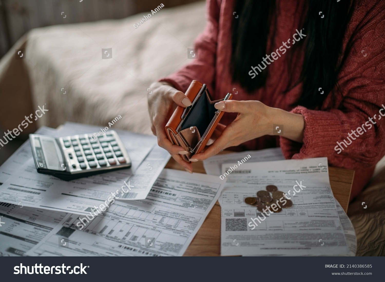 Close-up of woman's hands with empty wallet and utility bills. The concept of rising prices for heating, gas, electricity. Many utility bills, coins and hands in a warm sweater holding an open wallet #2140386585