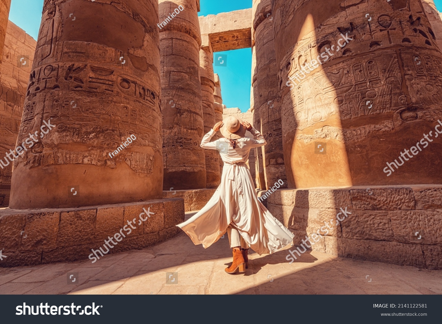 Woman traveler explores the ruins of the ancient Karnak temple in the city of Luxor in Egypt. Great row of columns with carved hieroglyph #2141122581
