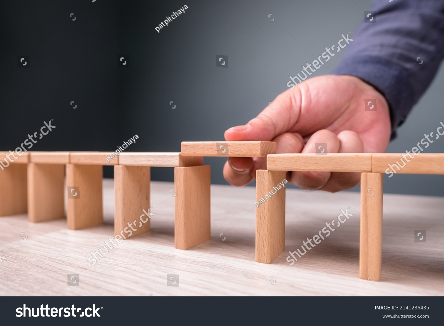 Hand build a toy bridge by wooden blocks and going to add the final piece between the gap to complete, concept of help solution, solve the disconnect problem #2141236435