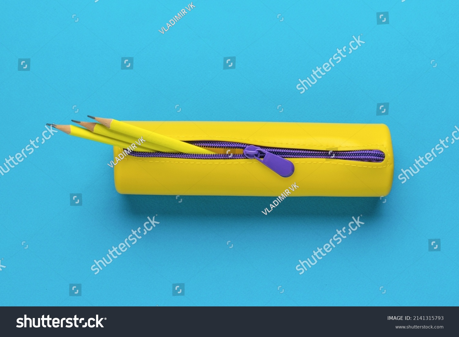 Yellow pencil case with three yellow pencils on a blue background. The minimum concept of storing school supplies. Flat lay. #2141315793