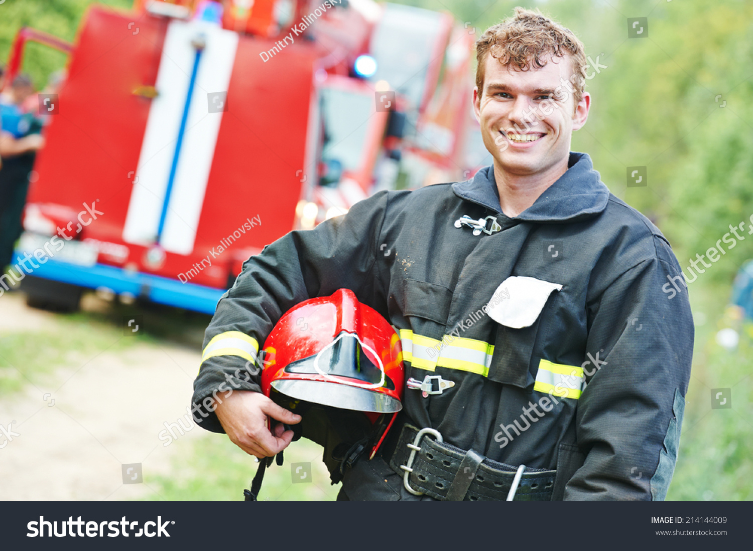 young smiling fireman firefighter in uniform in front of fire engine machine #214144009