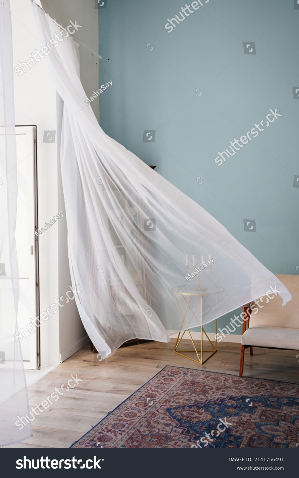 transparent fluttering curtain in the room with a candlestick on the table. romantic mood and spring weather. ventilation of premises. fresh wind. #2141756491