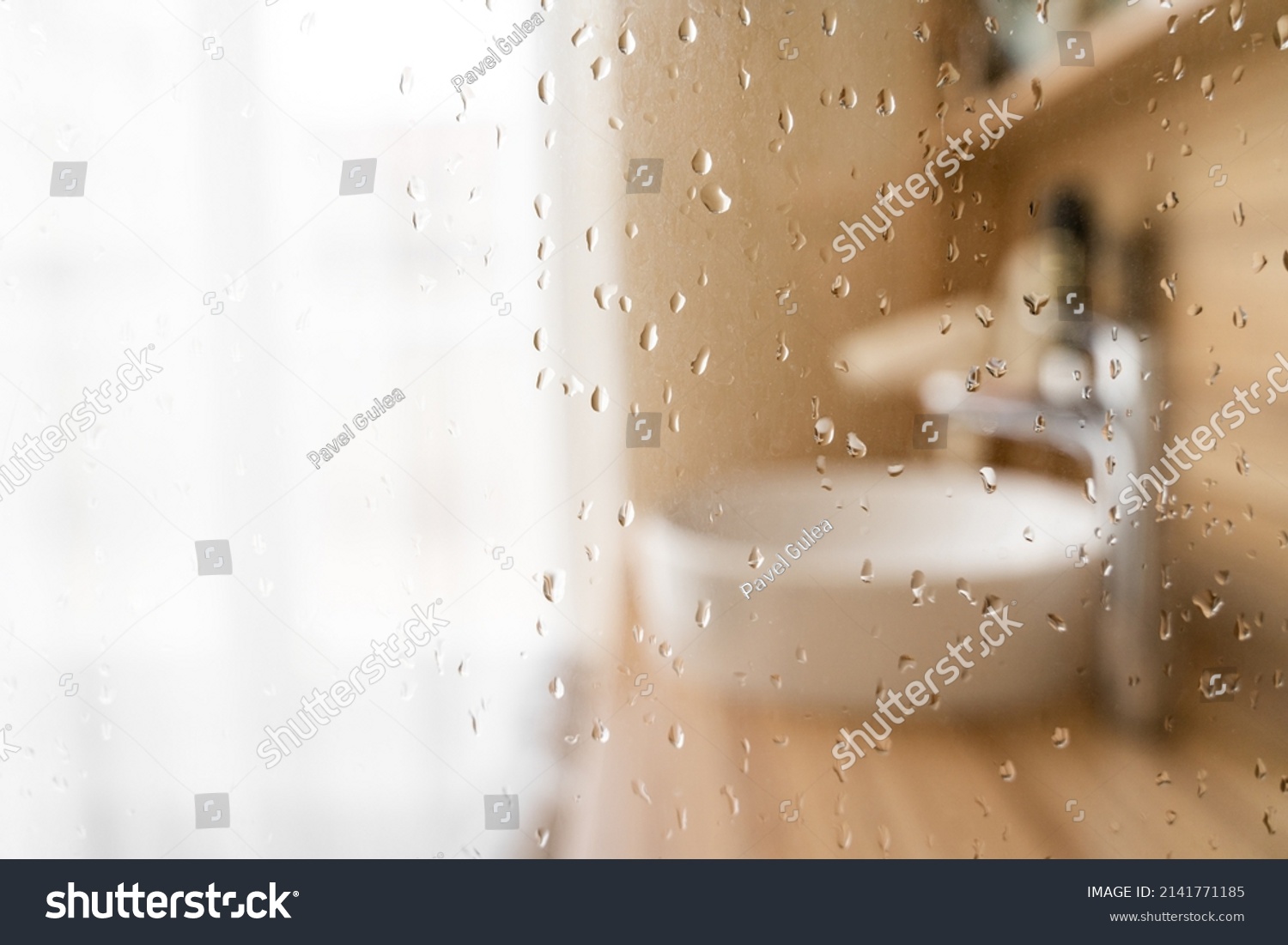 Water drops on wet glass shower door in hotel bathroom with blured bokeh window, sink, faucet and wooden furniture on sunny morning or day. Travel, holiday, vacation, interior design, body care #2141771185