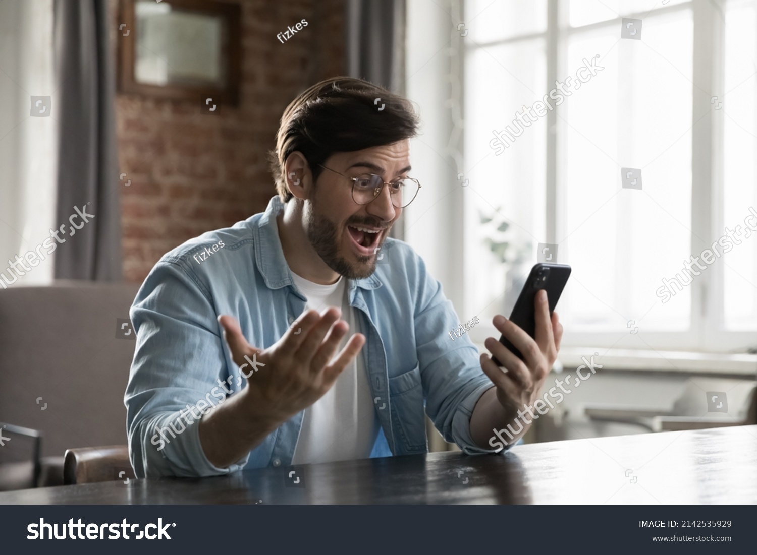 Excited smartphone user man staring at screen in surprise, reading text message getting good news, rejoicing at success, luck, happy opportunity, winning prize, gasping in shock, laughing, smiling #2142535929
