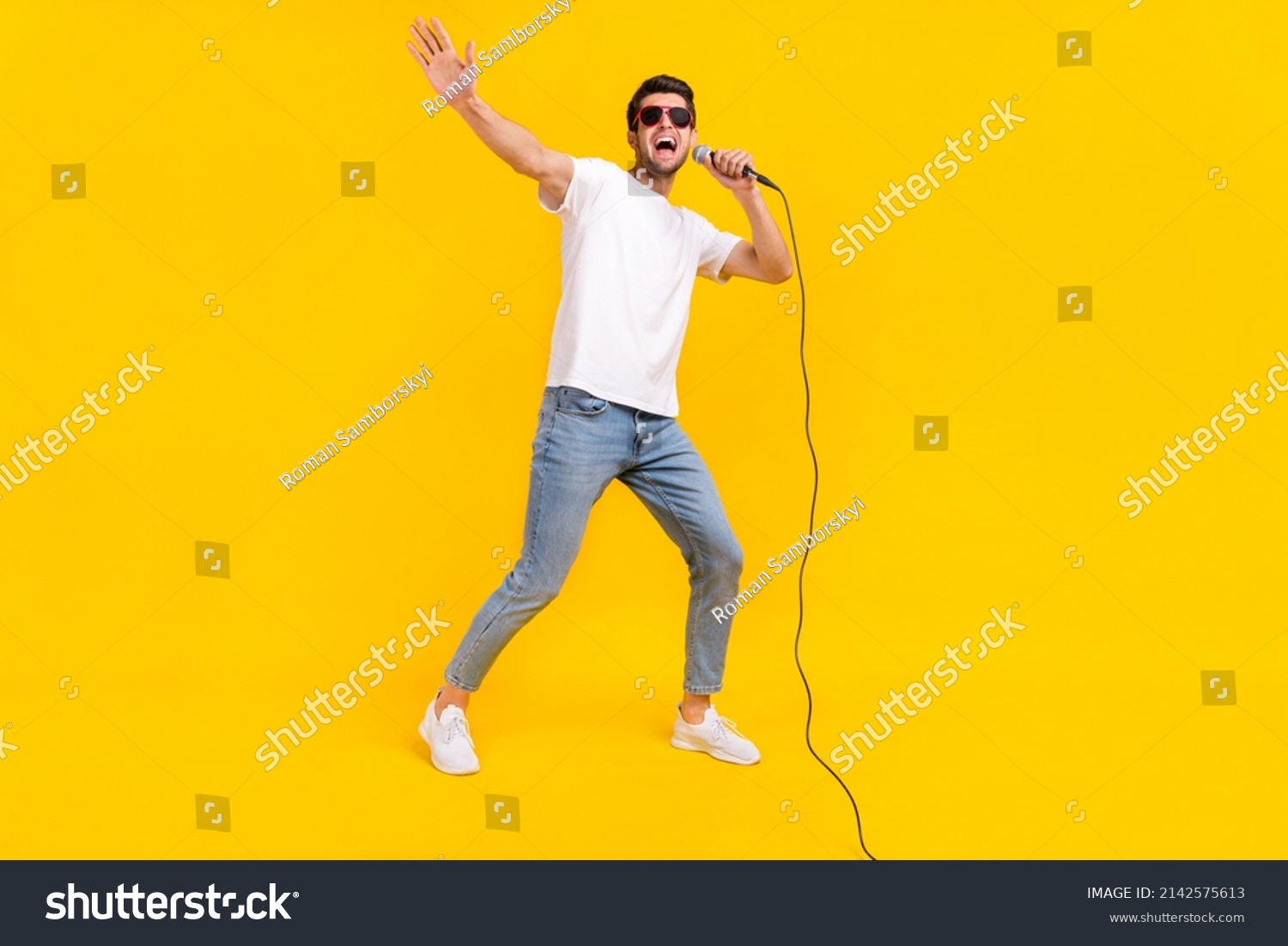 Full length photo of nice millennial brunet guy sing wear eyewear t-shirt jeans sneakers isolated on yellow background #2142575613