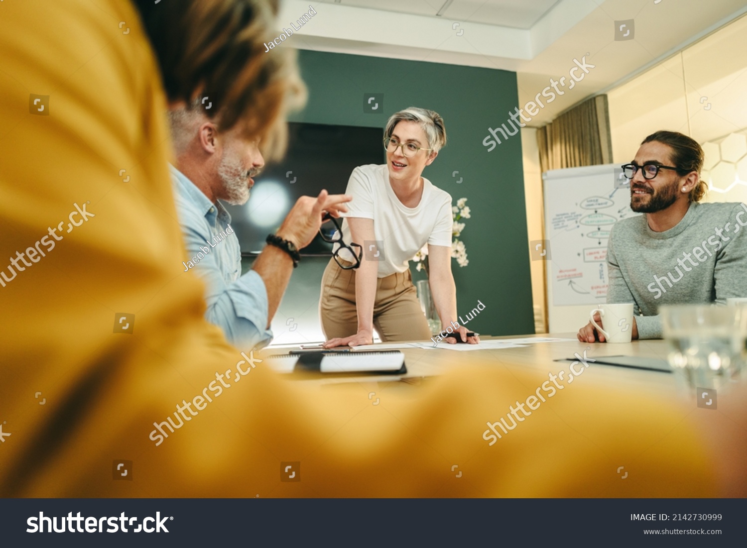 Happy businesspeople having a discussion in a boardroom. Group of cheerful business professionals sharing creative ideas during a meeting in a modern workplace. #2142730999