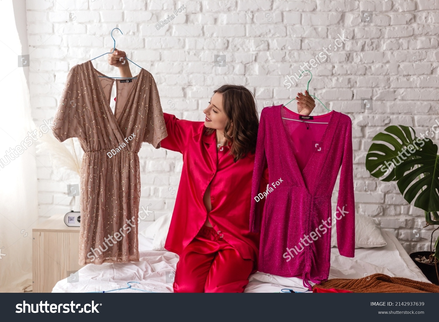 elegant woman in pajamas chooses a dress for a date. Stylish clothes, fashion #2142937639