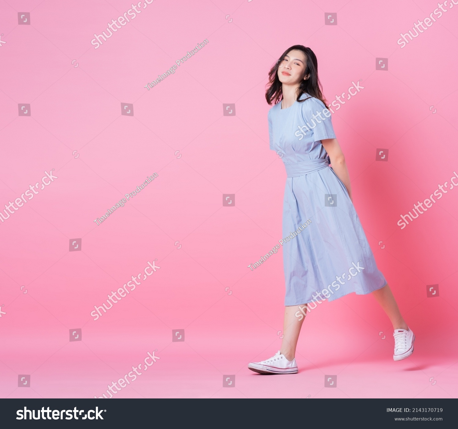 Full length image of young Asian woman wearing blue dress on pink background #2143170719