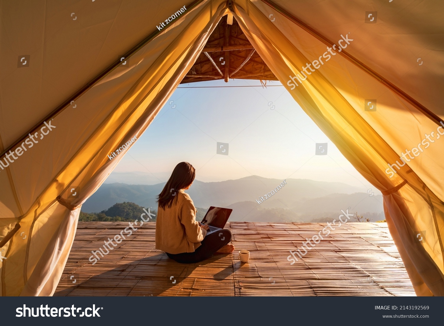Young woman freelancer traveler working online using laptop and enjoying the beautiful nature landscape with mountain view at sunrise #2143192569
