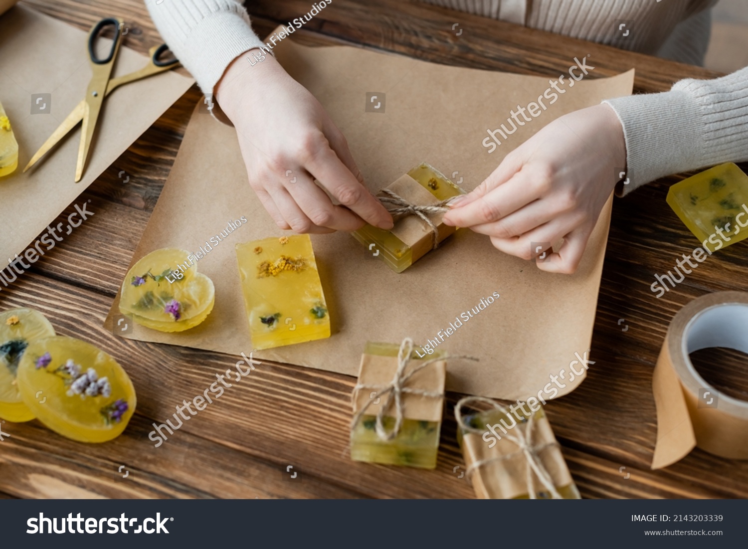 craftswoman packaging handmade soap on craft paper on table #2143203339