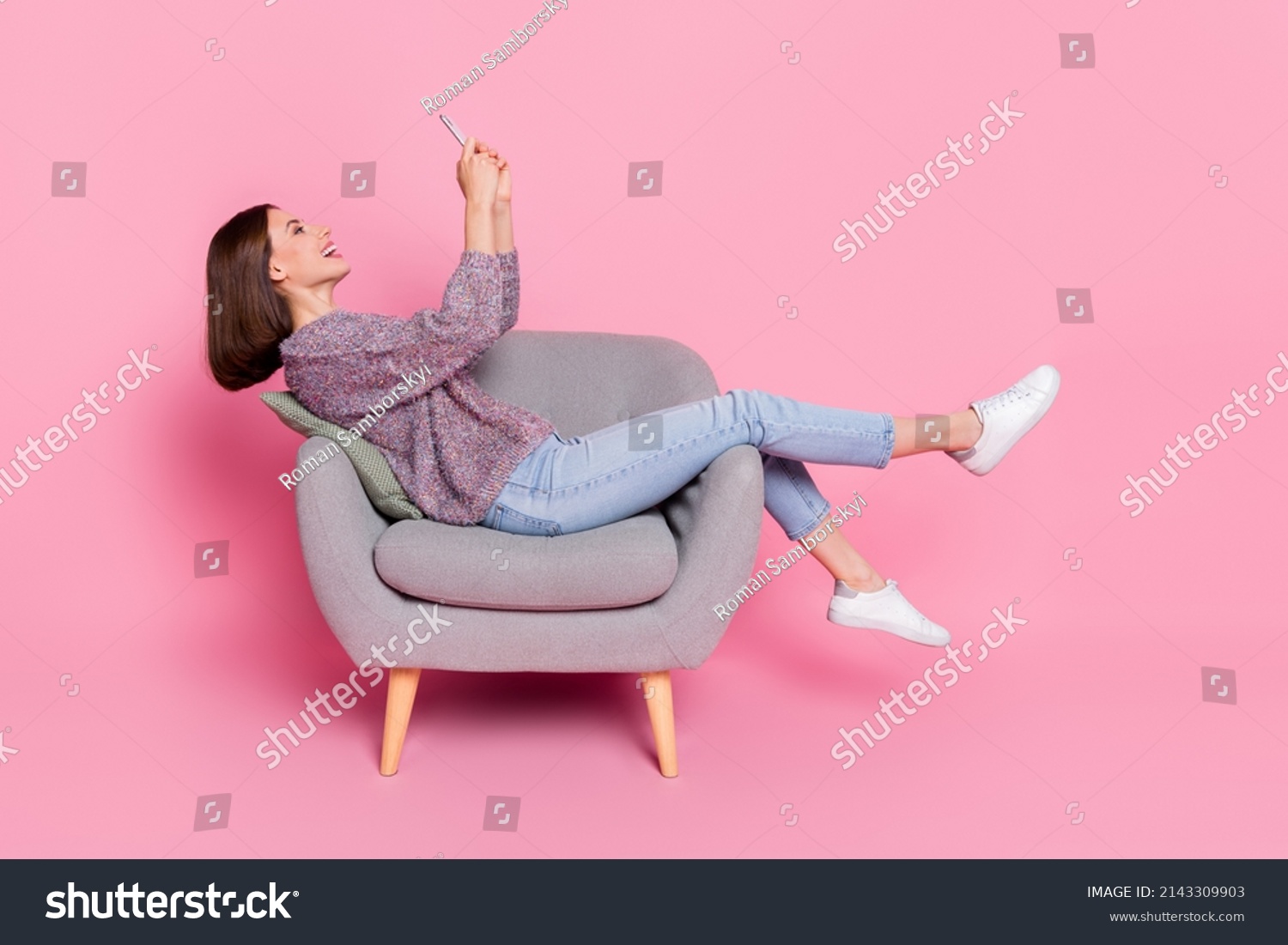 Profile side view portrait of attractive cheerful girl sitting in armchair using device isolated over pink pastel color background #2143309903