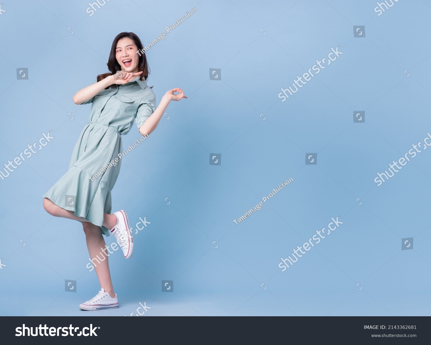 Full length image of young Asian woman wearing dress on blue background #2143362681