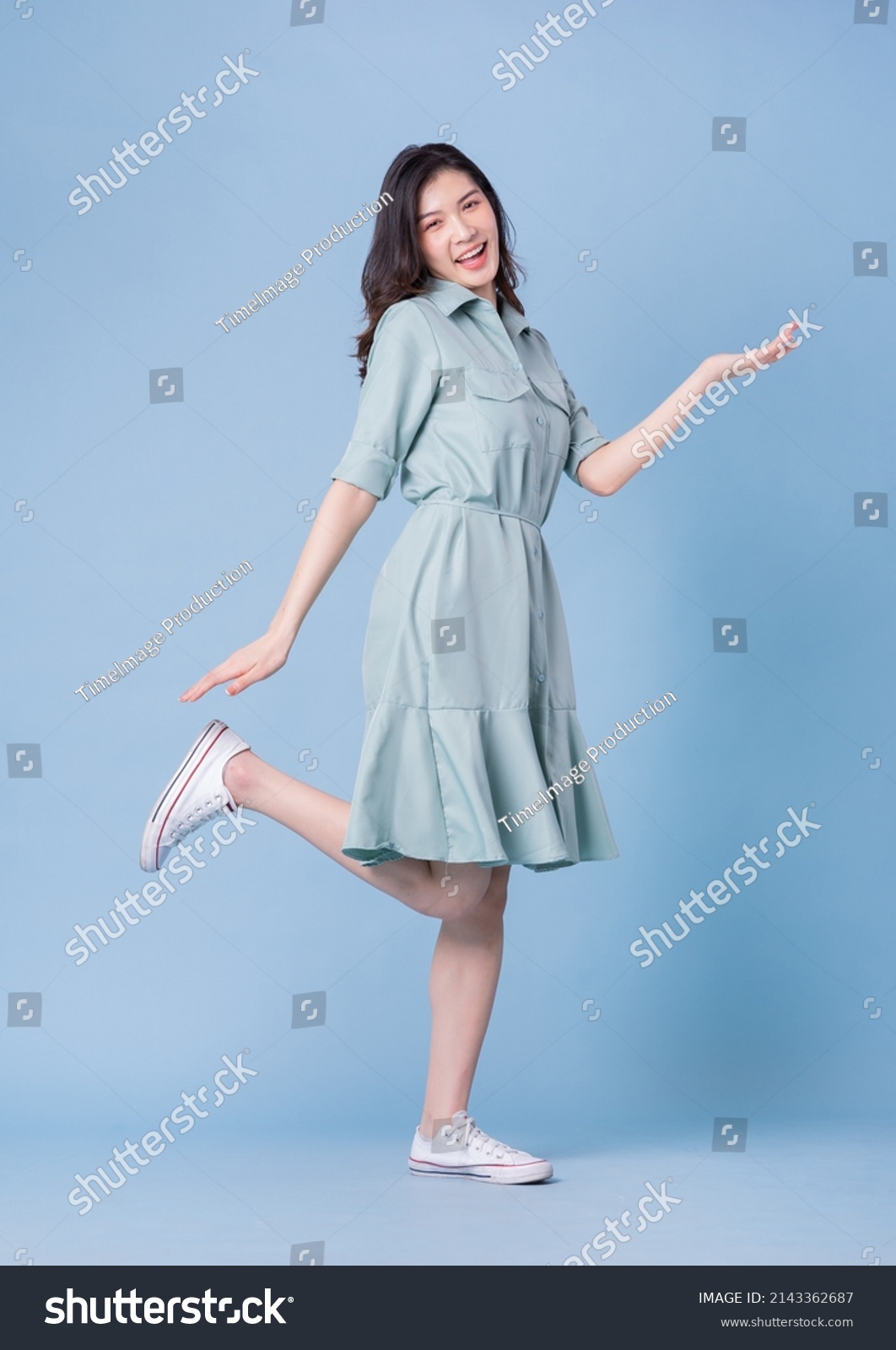 Full length image of young Asian woman wearing dress on blue background #2143362687