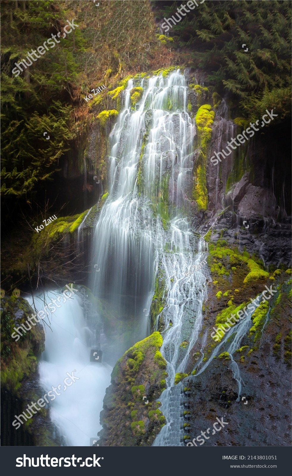 A mountain waterfall flows over the rocks. Waterfall cascade on mossy rocks #2143801051