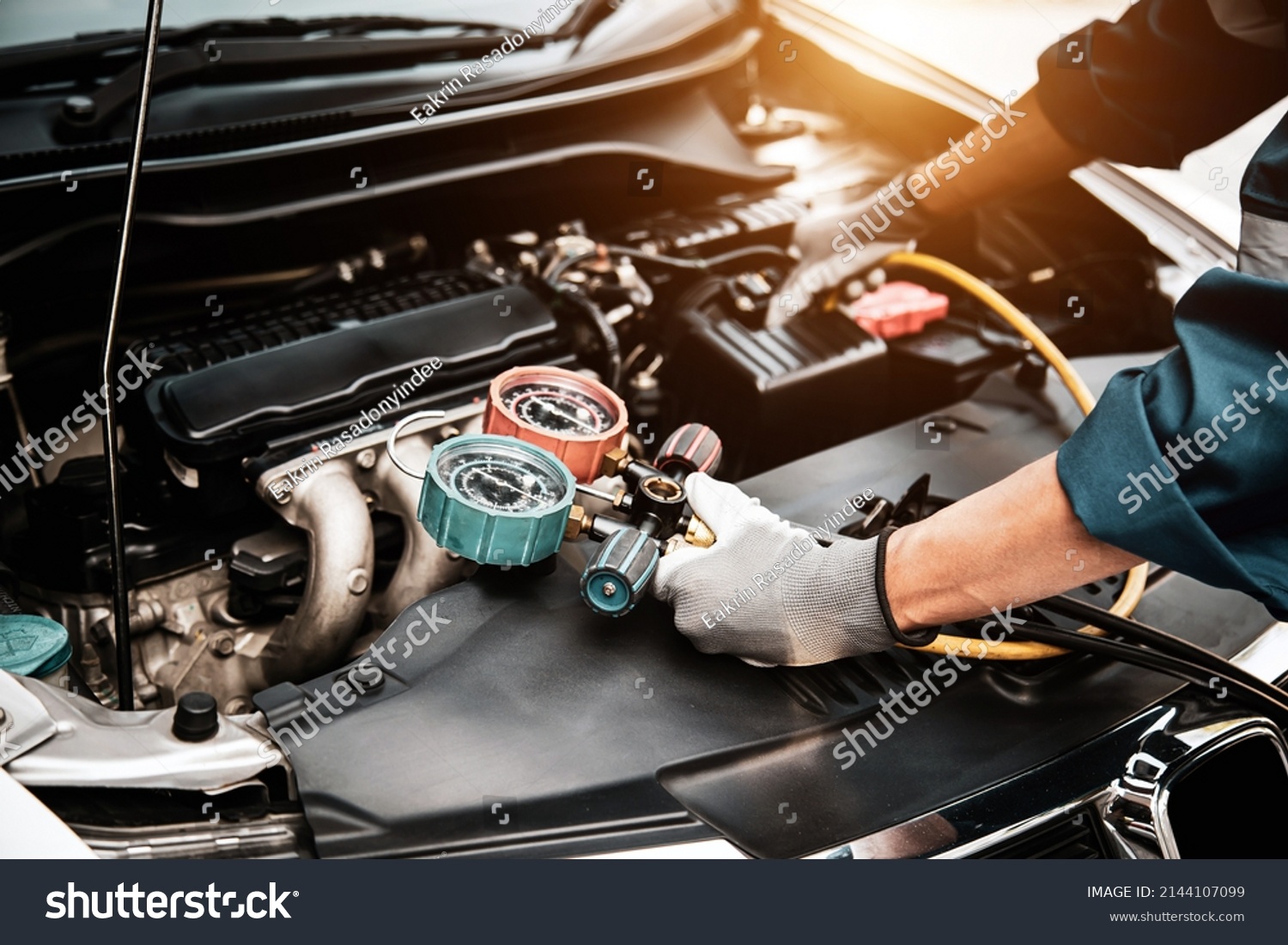 Close up hand of auto mechanic using measuring manifold gauge check the refrigerant and filling car air conditioner for fix and checking for repair service support maintenance and car insurance. #2144107099