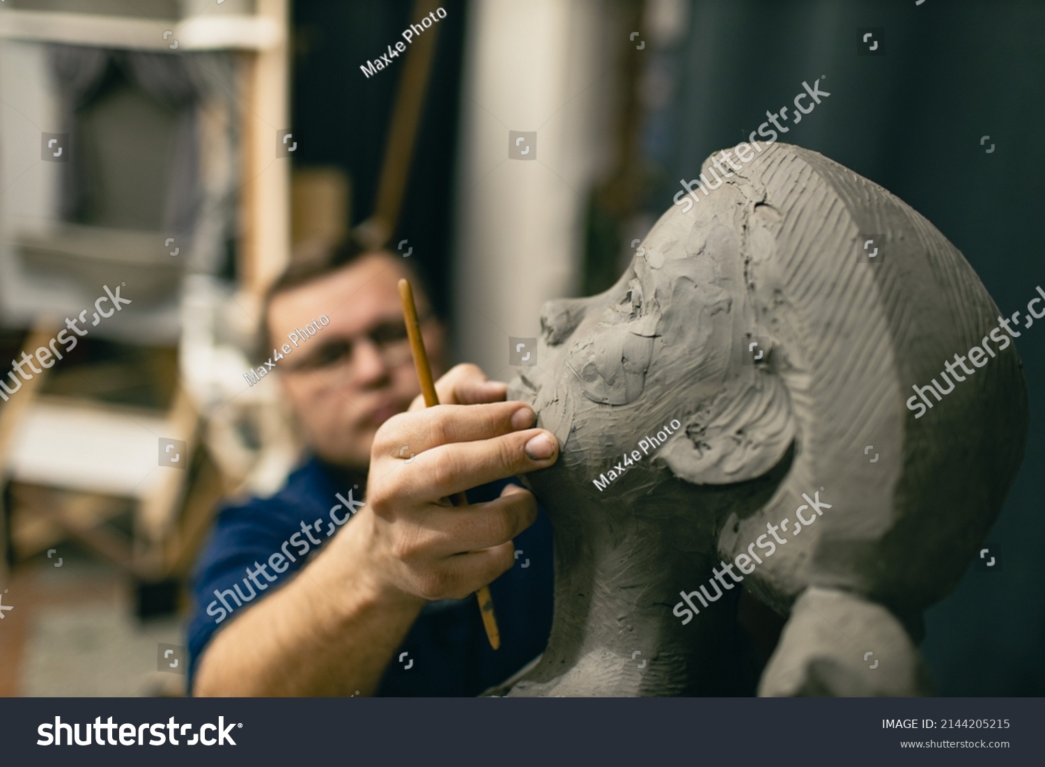 Man sculptor creates sculpt bust clay human woman sculpture. Statue craft creation workshop. #2144205215