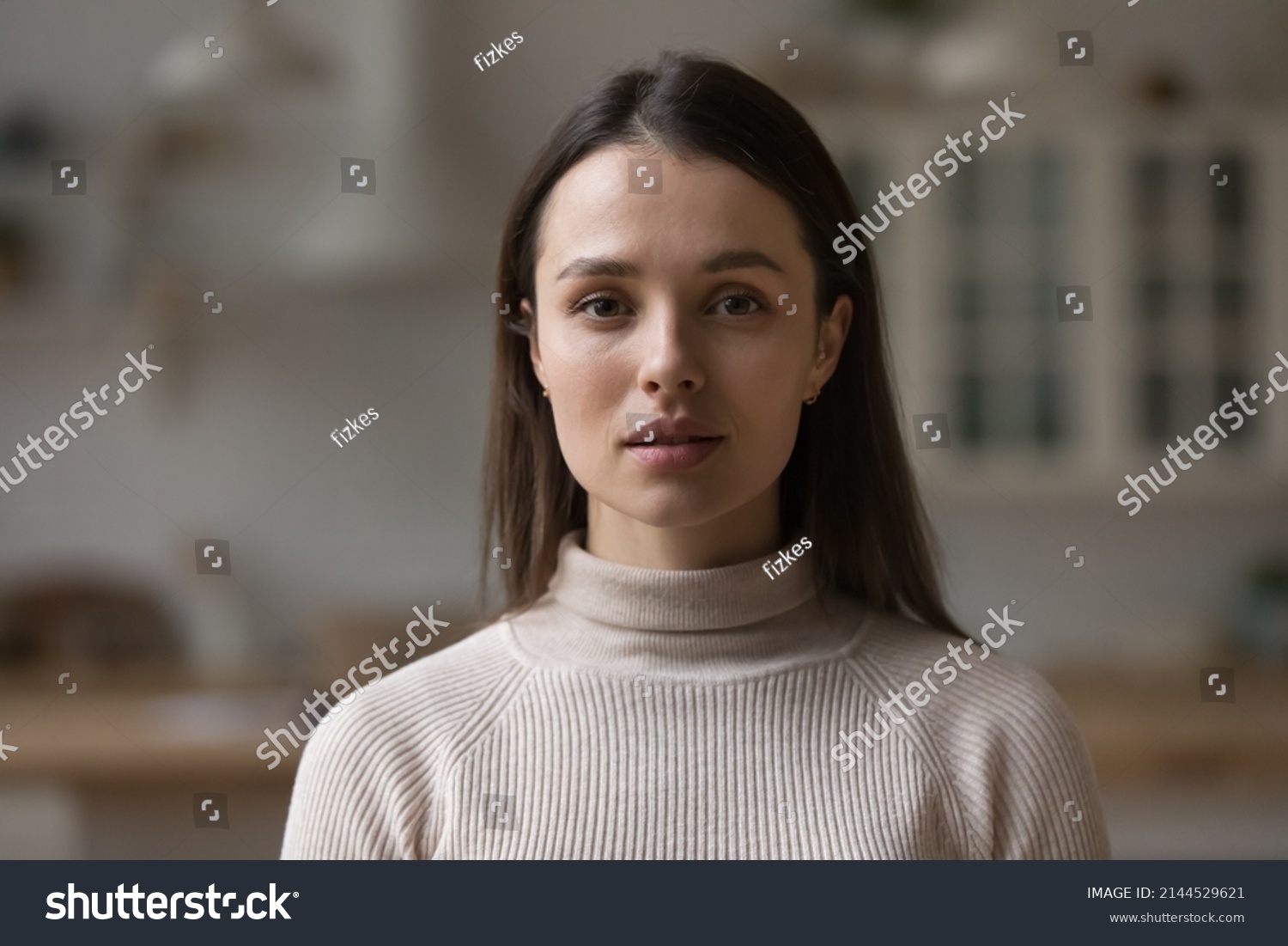 Positive serious millennial model girl home female head shot portrait. Beautiful young adult Caucasian woman looking at camera, posing in apartment. Front profile picture #2144529621