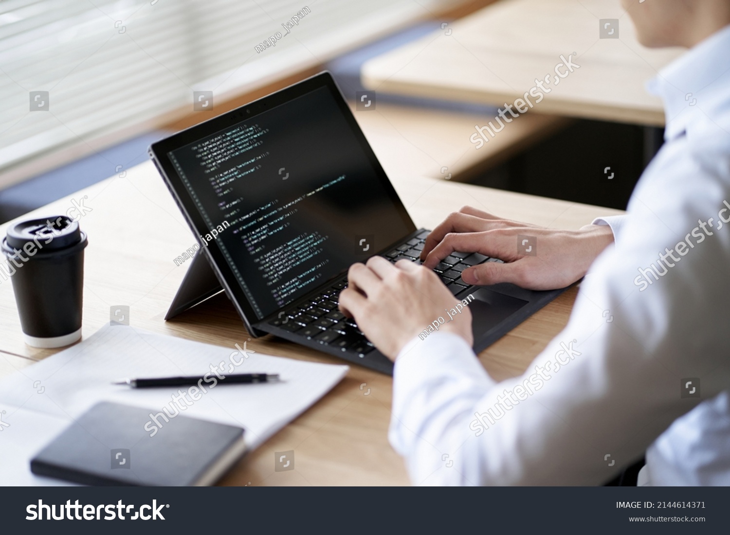 Asian programmer writing code on a laptop #2144614371