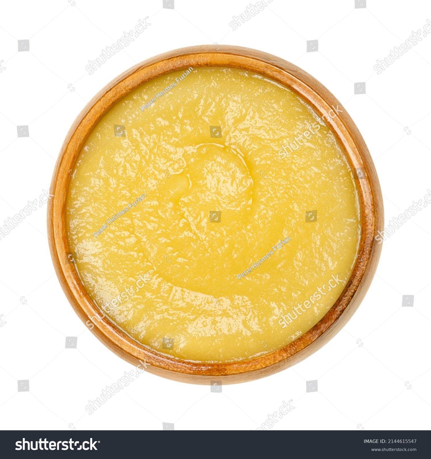 Apple sauce in a wooden bowl. Commercially processed applesauce, a yellow sauce made of peeled and cooked apples. Inexpensive and widely consumed in North America and parts of Europe. Macro food photo #2144615547