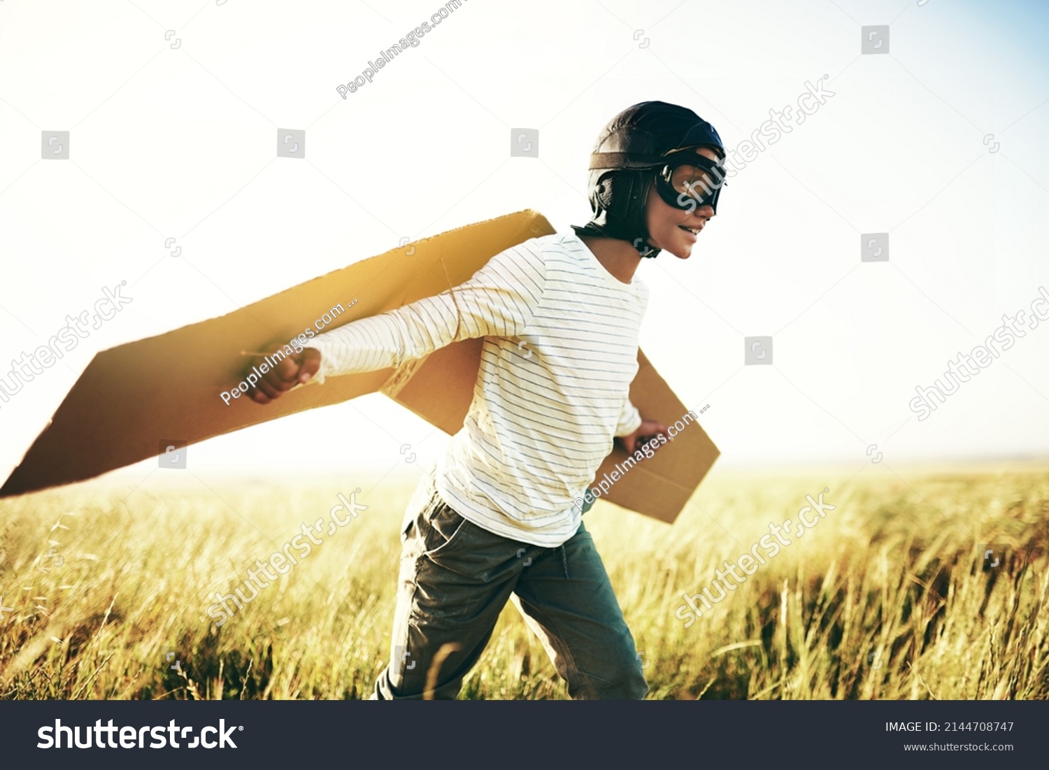 Ready for lift off. Shot of a young boy pretending to fly with a pair of cardboard wings in an open field. #2144708747