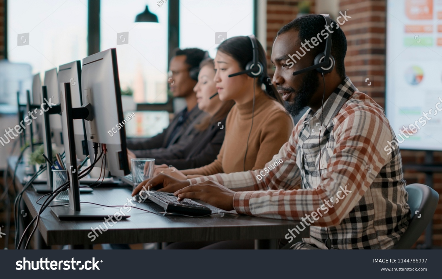 African american man working at call center office to help people with telemarketing assistance. Male employee using headphones and microphone at customer care service. Tripod shot. #2144786997