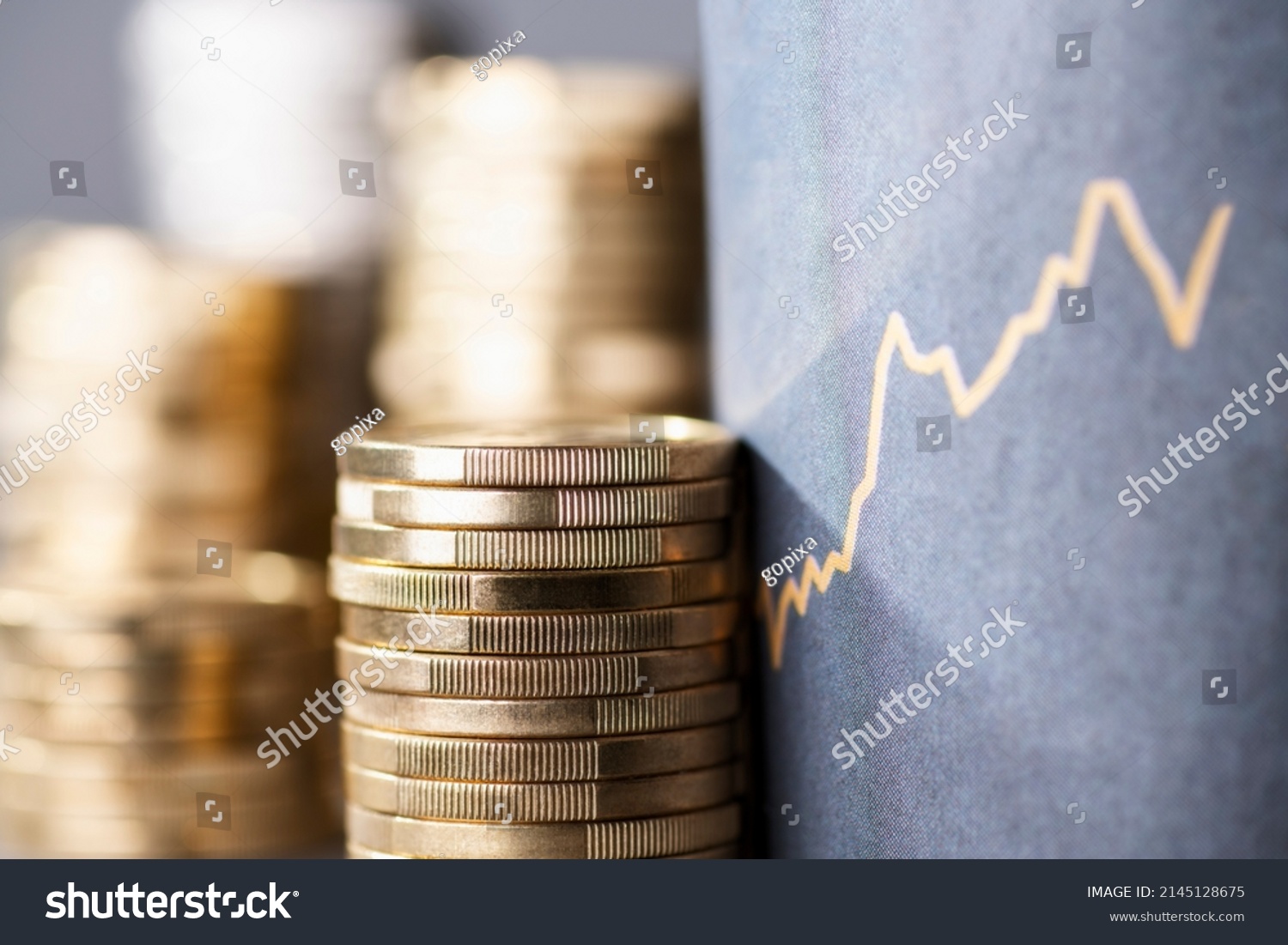 Stack of coins next to a upward curve symbolizing rising costs due to inflation #2145128675