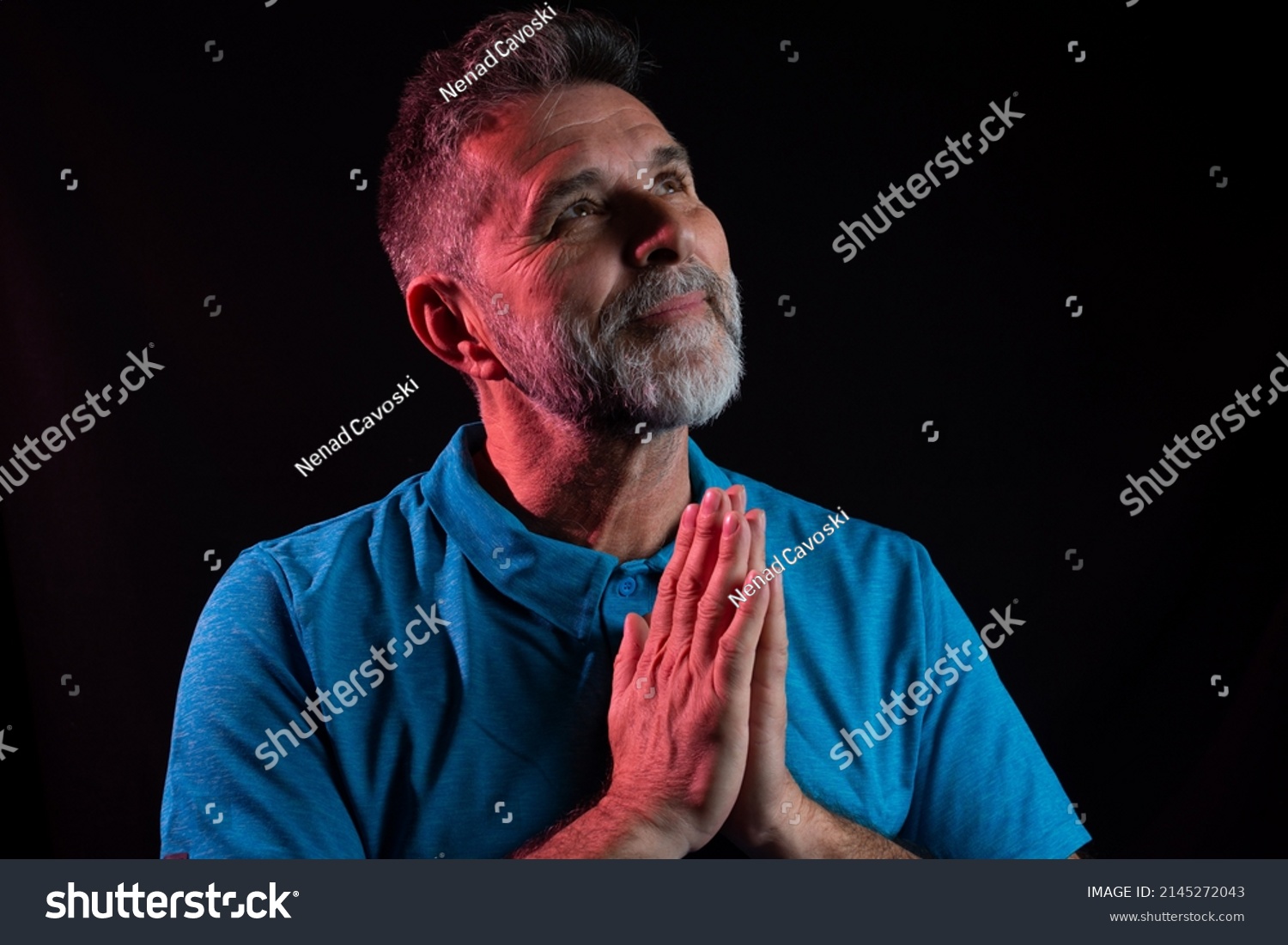 Closeup portrait mature man praying hands clasped hoping for best asking for forgiveness or miracle. Christian faith towards God concept. Concept for religion, faith, prayer and spirituality. Black.  #2145272043