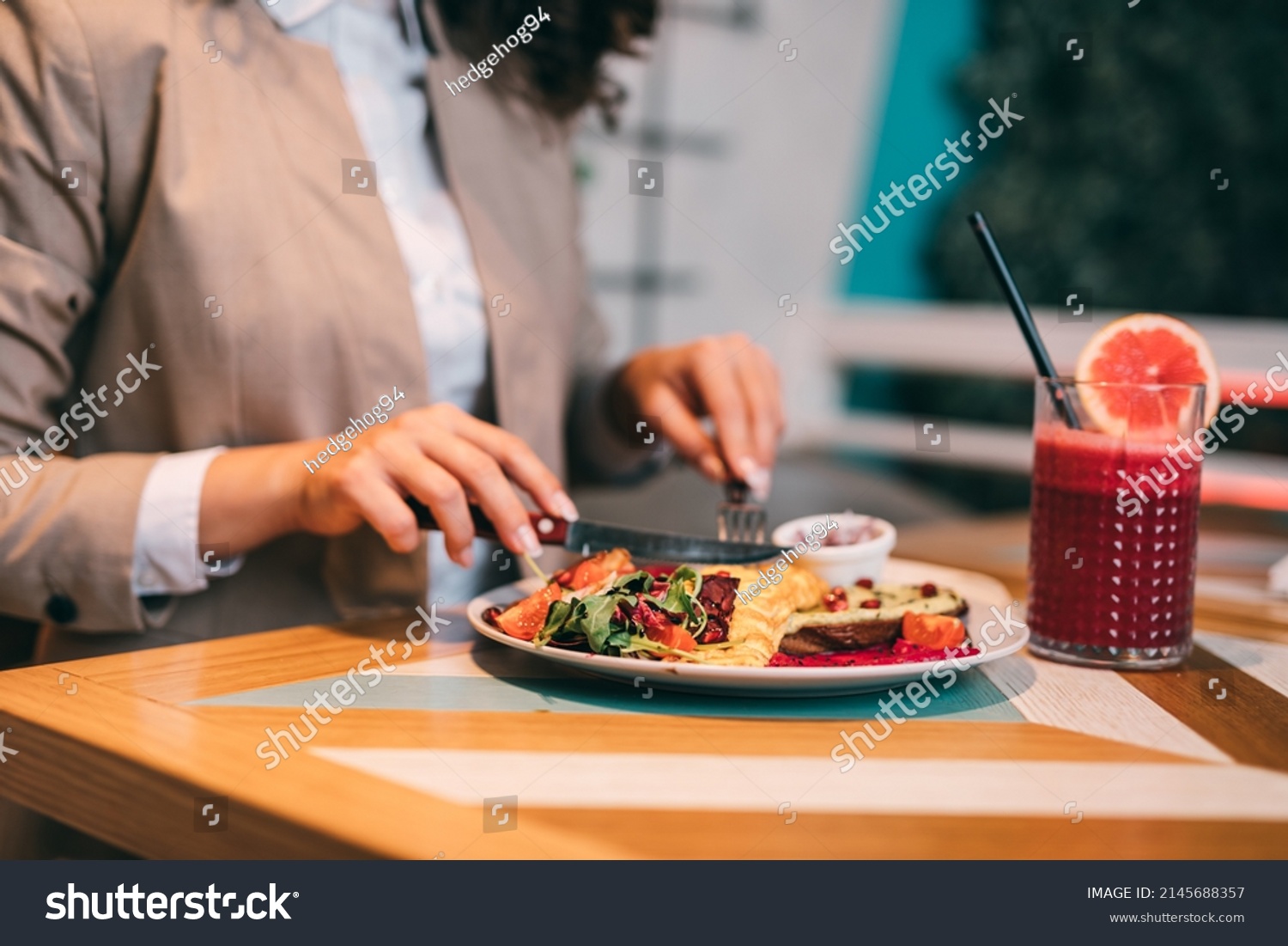 A middle-aged businesswoman enjoys a healthy meal and fresh beetroot and grapefruit juice at the organic food restaurant. #2145688357