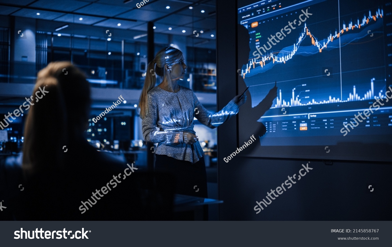 Business Conference Meeting Presentation: Businesswoman does Financial Analysis talks to Group of Businessspeople. Projector Screen Shows Stock Market Data, Investment Strategy, Revenue Growth #2145858767