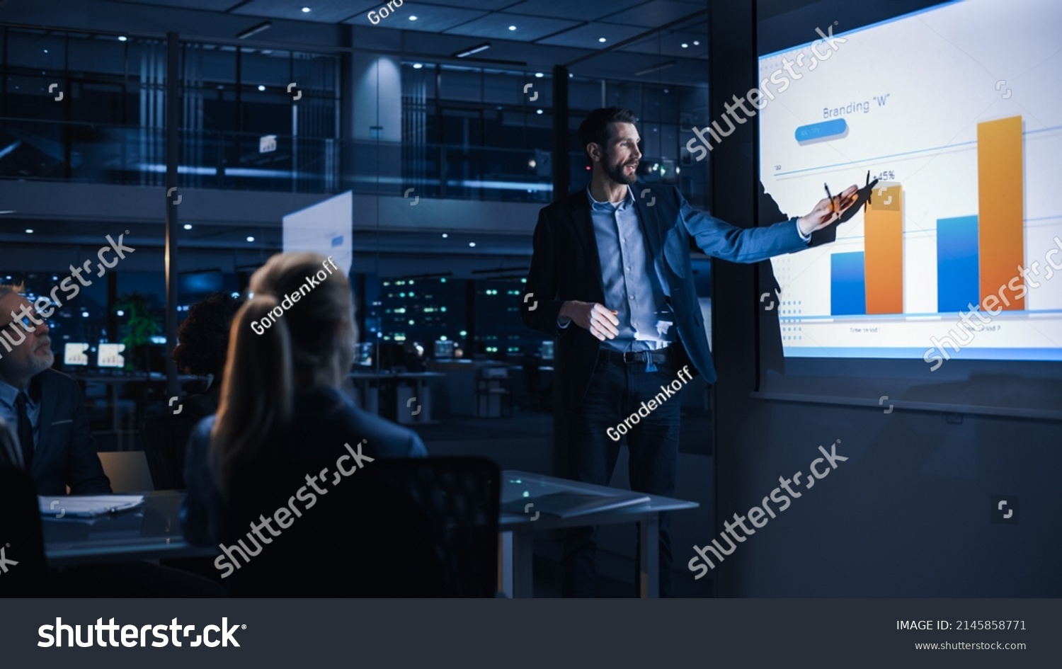 Conference Business Meeting Presentation: CEO Businessman Shows Data to Group of Investors, Businessspeople. Projector Screen Shows Graphs, Product Sales, Revenue Growth Strategy, e-Commerce Analysis #2145858771