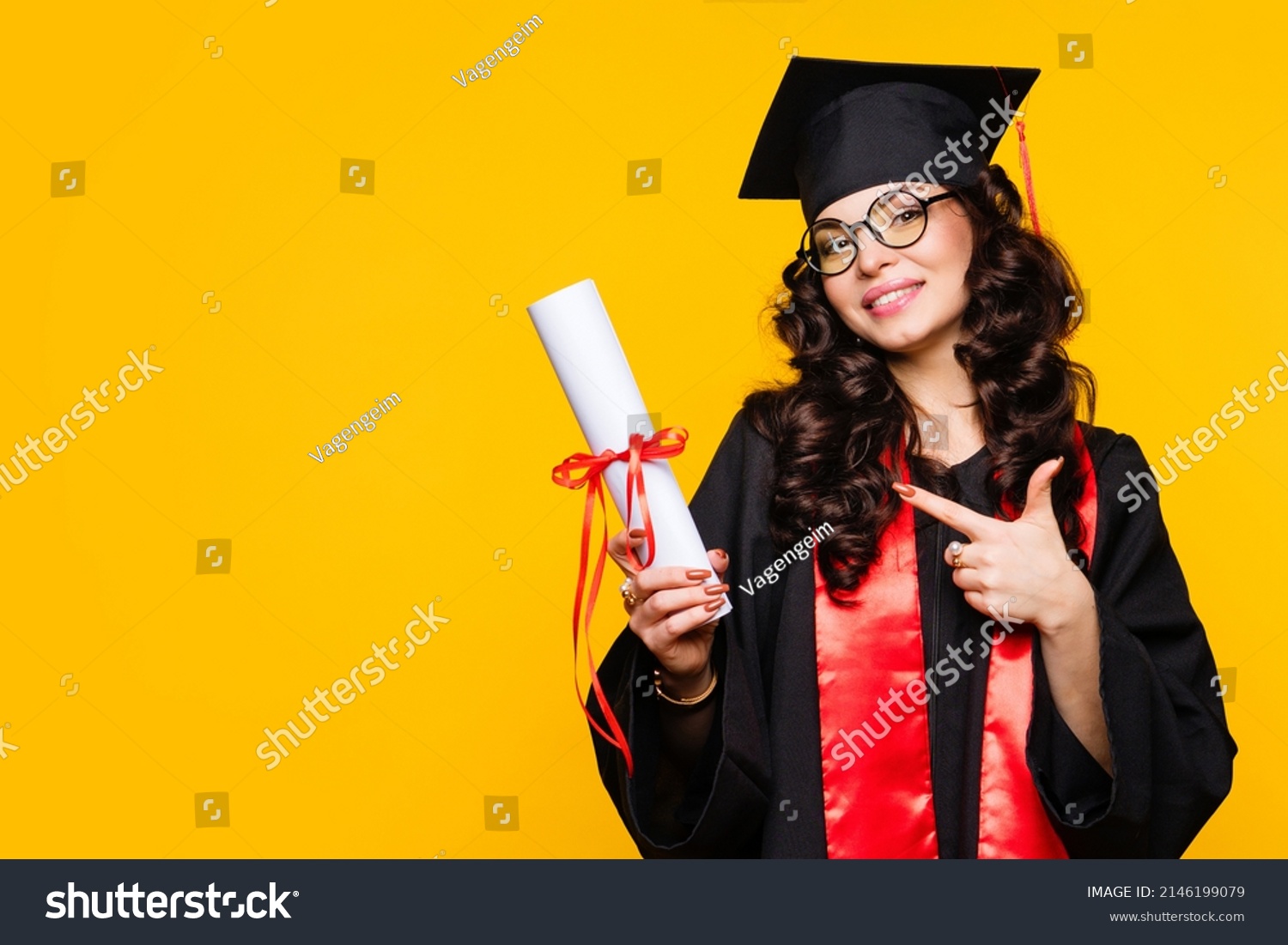 Girl graduate in graduation hat and eyewear with diploma on yellow backdrop. Brunette young woman wearing graduation cap and ceremony robe holding Certificate tied with red ribbon. Education Concept  #2146199079