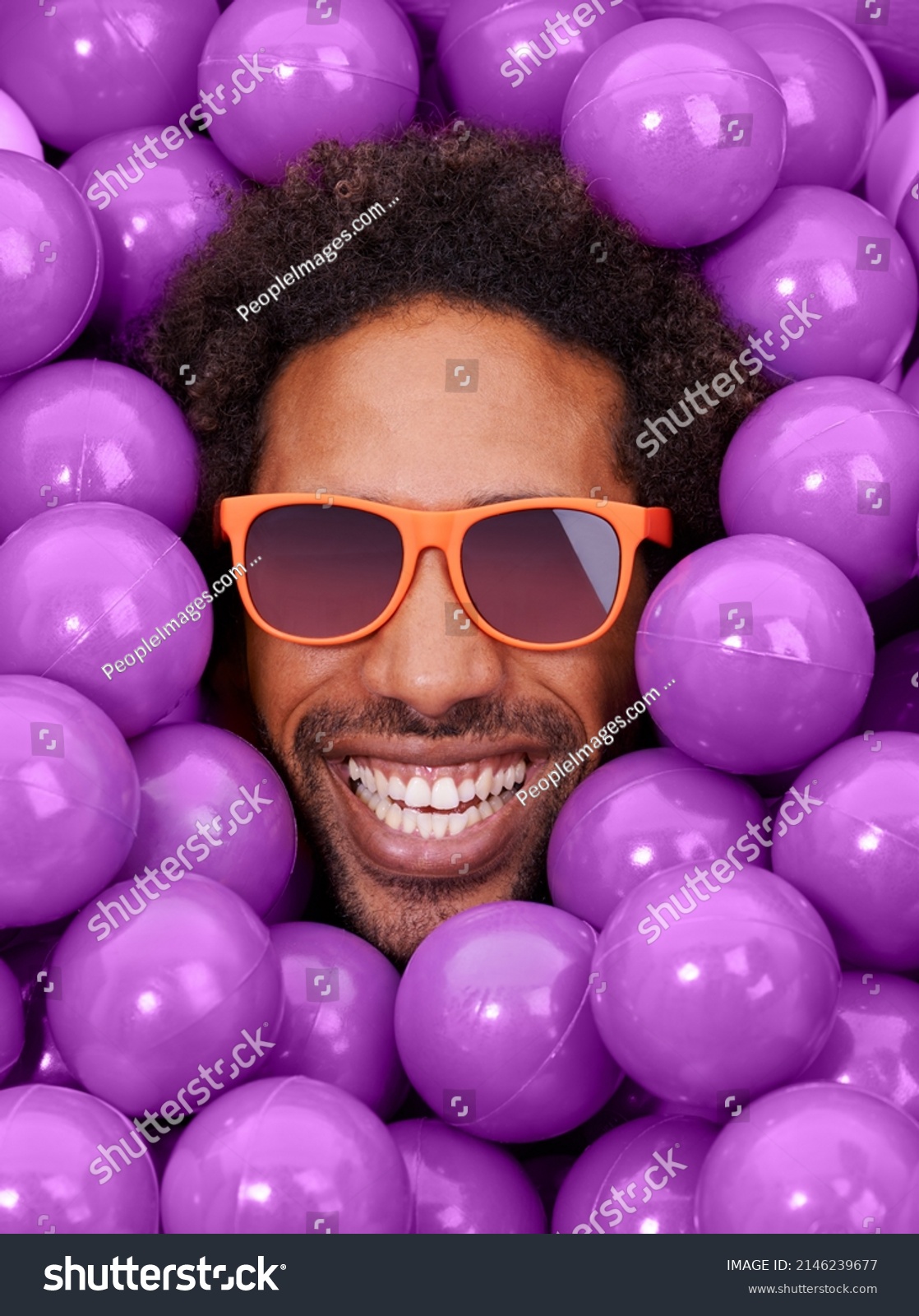 Looking cool and crazy. A young black mans face amongst purple pit balls. #2146239677