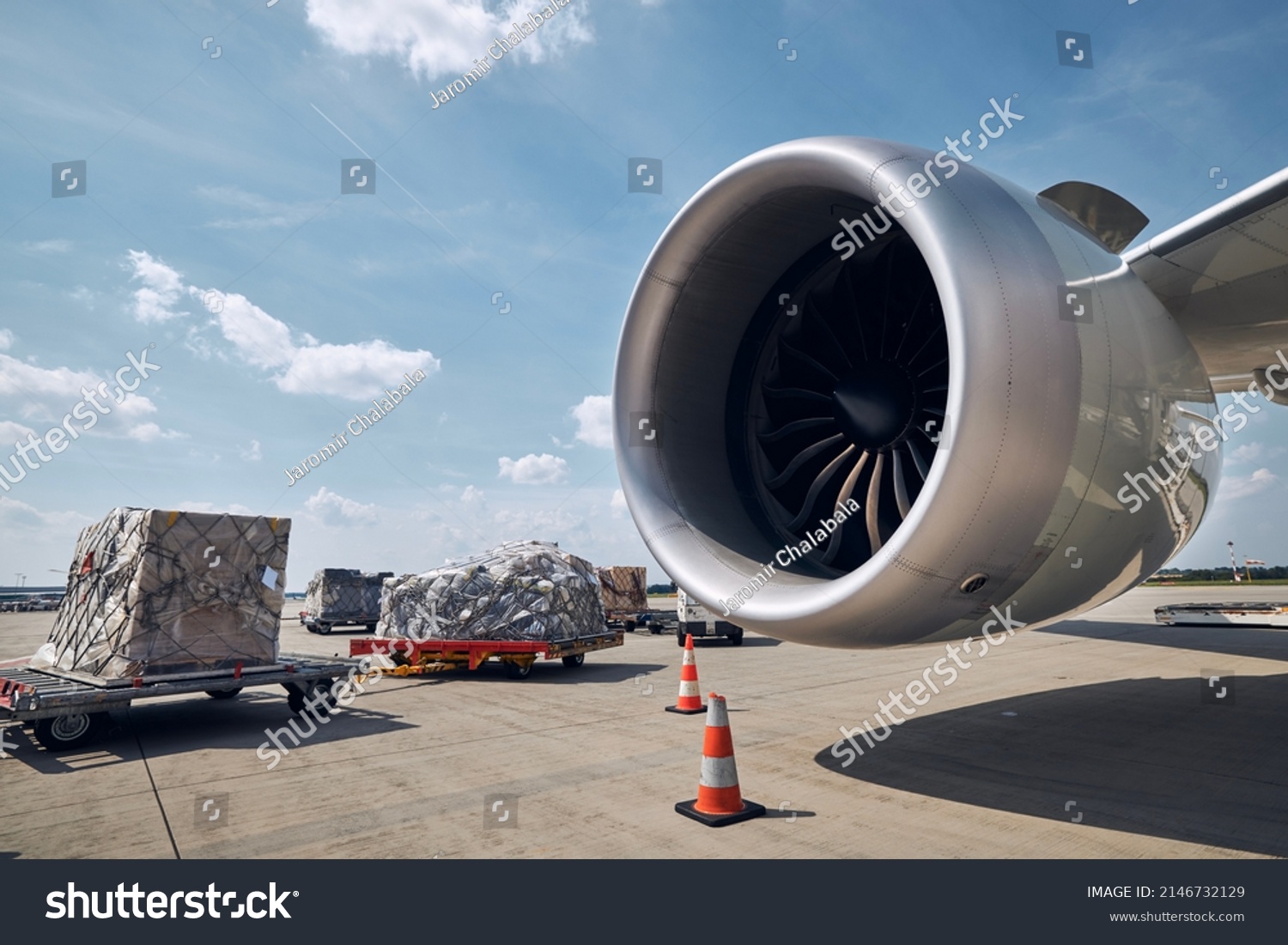 Preparation freight airplane at airport. Loading of cargo containers against jet engine of plane. #2146732129