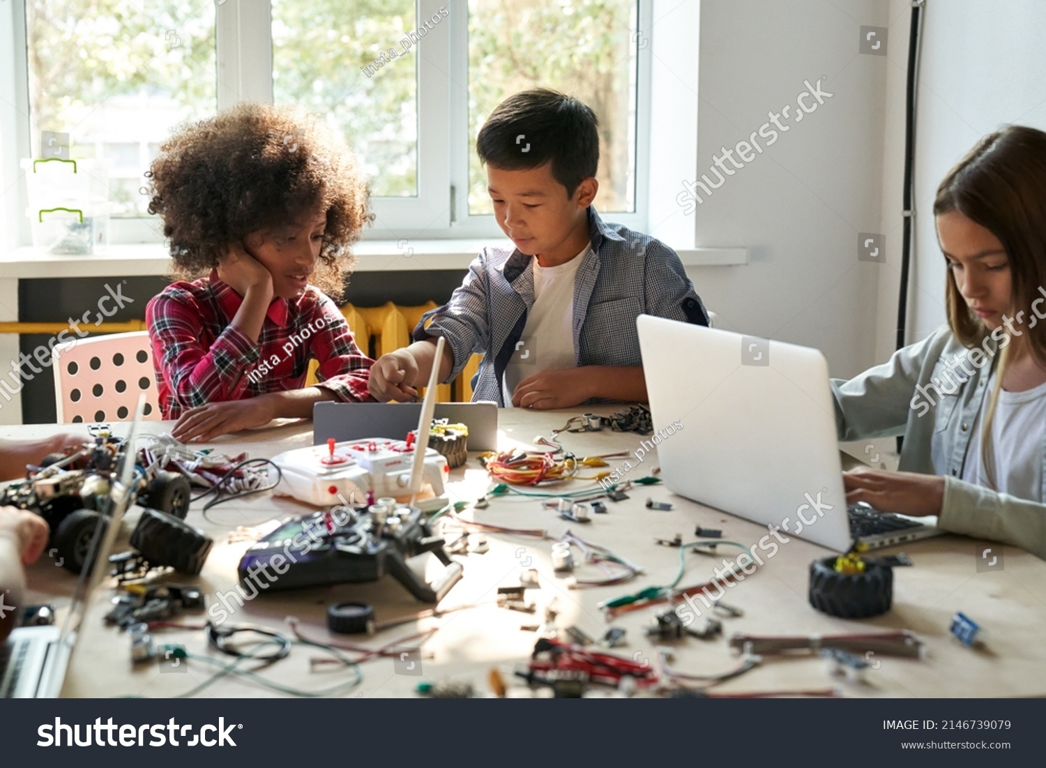 Afro American girl and Asian boy schoolkids using tablet device developing program for software robotics engineering and building at school lab. AI technologies development. STEM education. Vertical. #2146739079