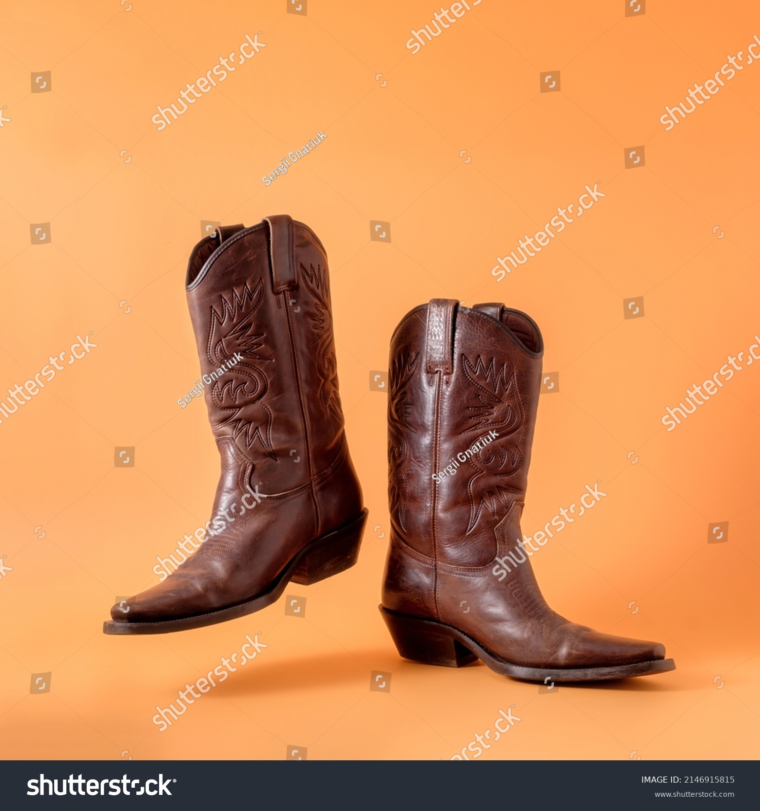Two elegant classic cowboy boots on an orange clay background. Ranger cowboy concept on a ranch in america usa texas. #2146915815