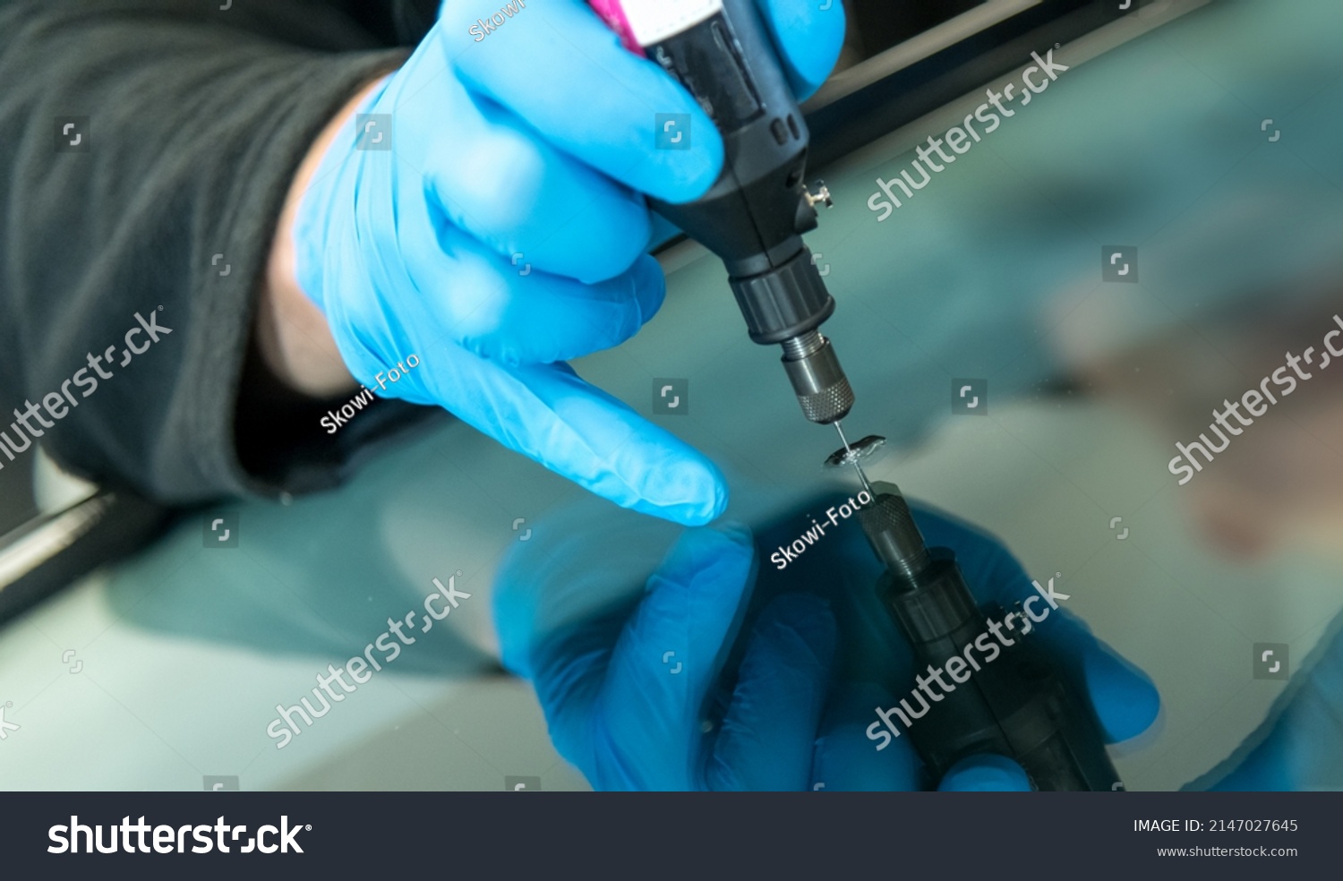 mechanic is repairing an stone chip using his glass repair equipment #2147027645