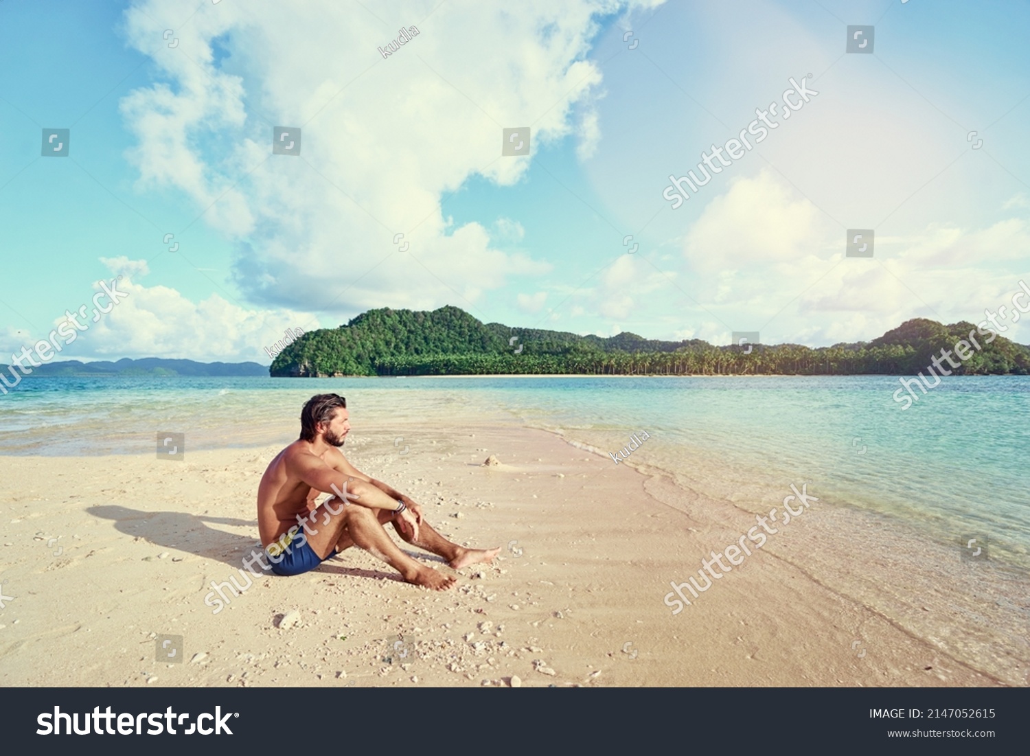Tropical vacation. Relaxed young man sitting on the sand beach enjoying the island view. #2147052615