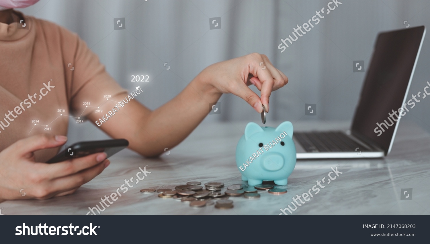 money saving concept Close your hands and put coins in the piggy bank for saving money. A smart woman holds a silver coin and prepares to put it in a piggy bank. with annual graph #2147068203
