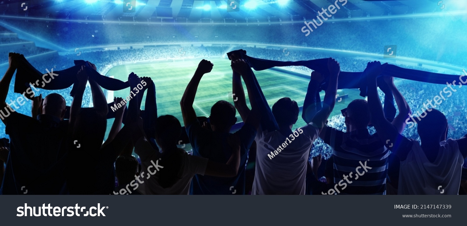 At world cup. Back view of football, soccer fans cheering their team with state flags and scarfs at crowded stadium at evening time. Concept of sport, cup, world, team, event, competition #2147147339