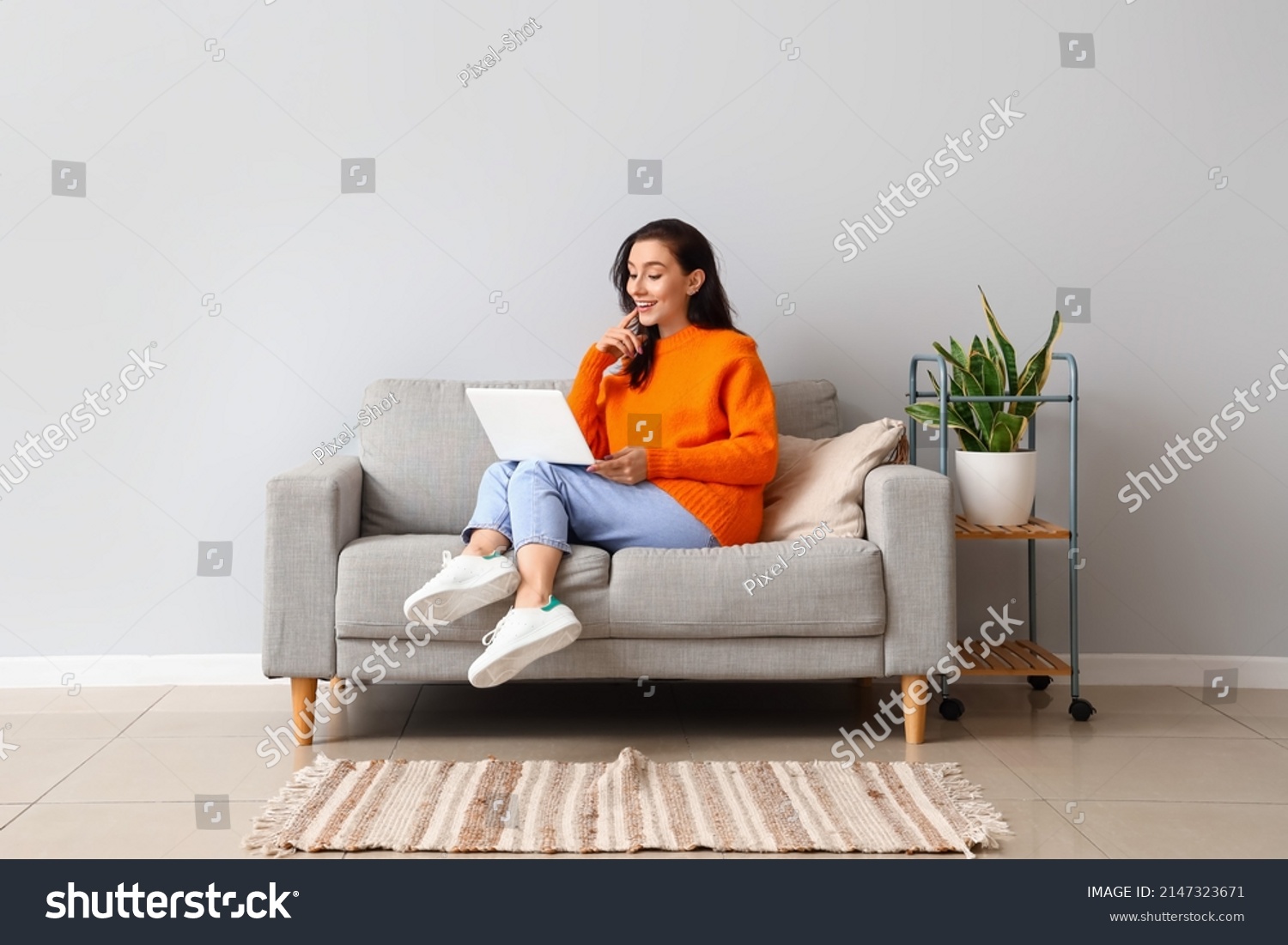 Beautiful young woman with laptop resting on couch at home #2147323671