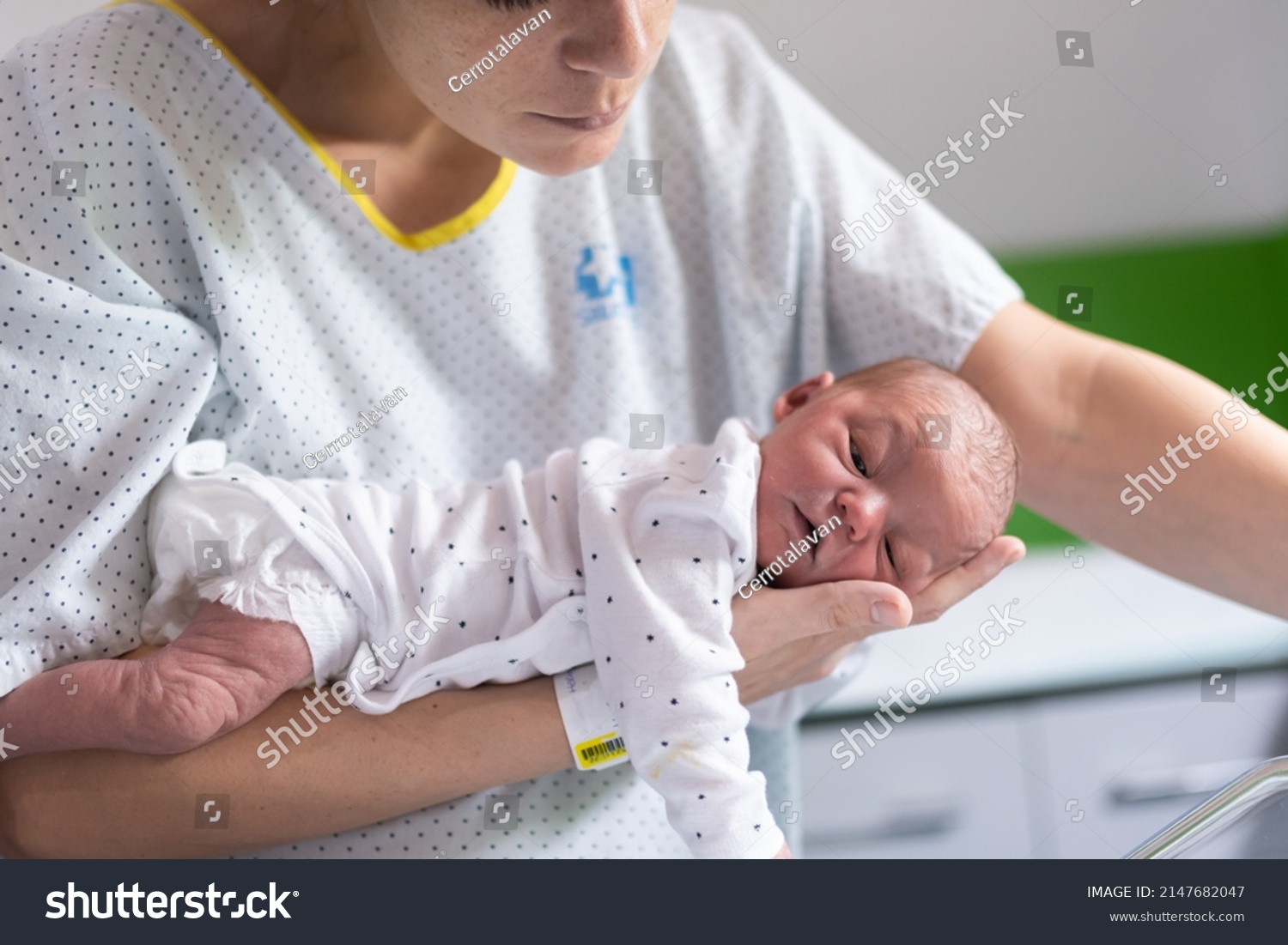 mom who has just given birth in the hospital holds her newborn baby in her arms face down to get rid of gas and prevent colic in the infant. newborn health and care #2147682047