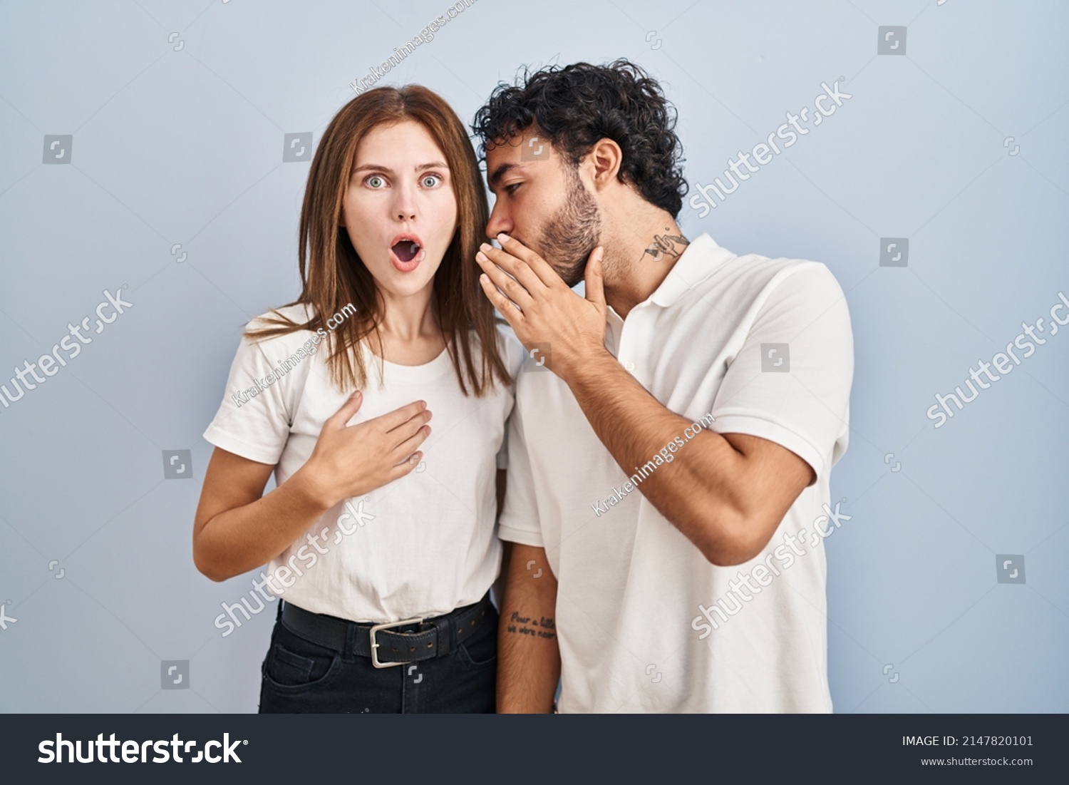 Young couple wearing casual clothes standing together hand on mouth telling secret rumor, whispering malicious talk conversation  #2147820101