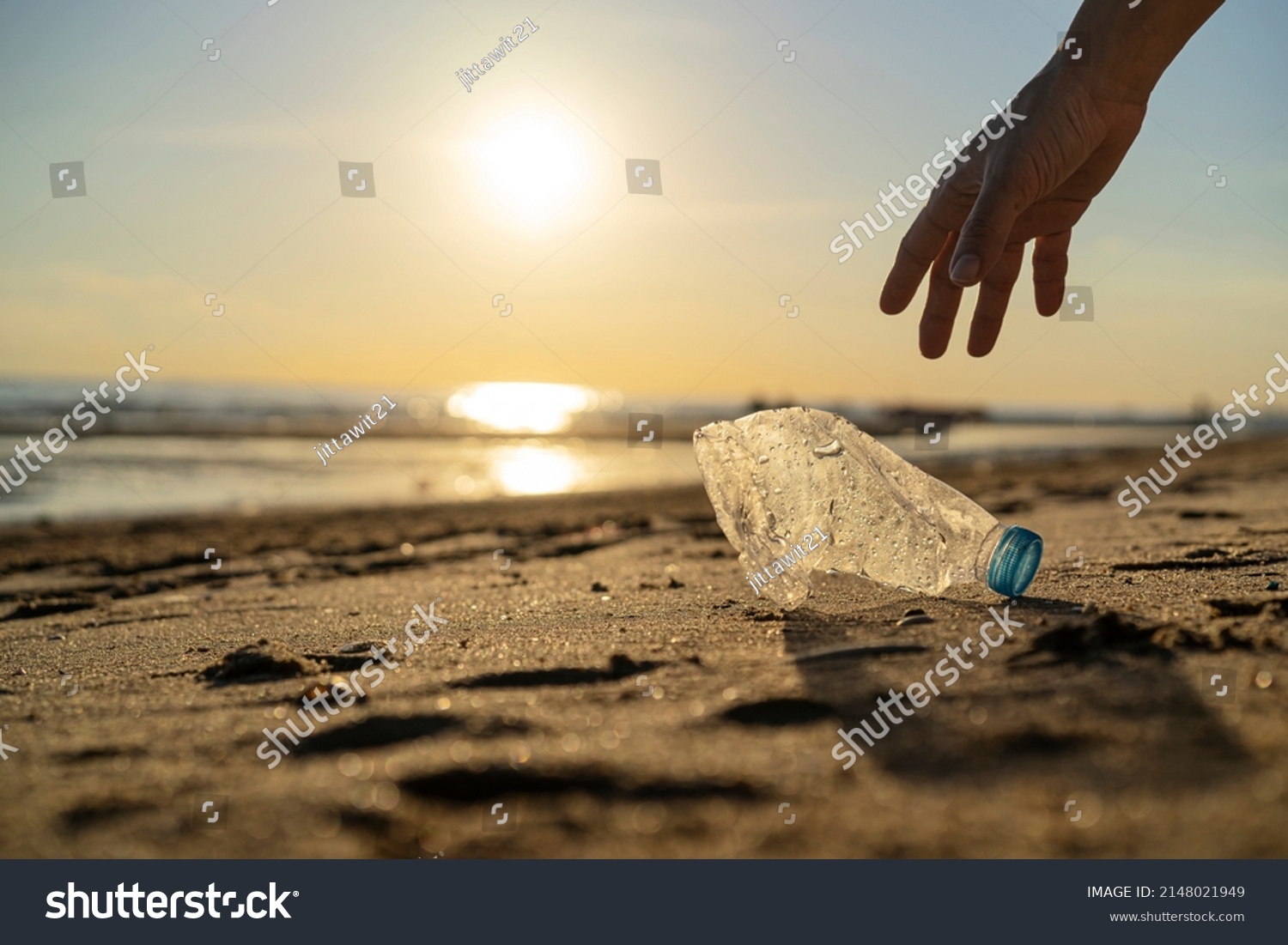 Volunteer man and plastic bottle, clean up day, collecting waste on sea beach, pollution and recycling concept #2148021949