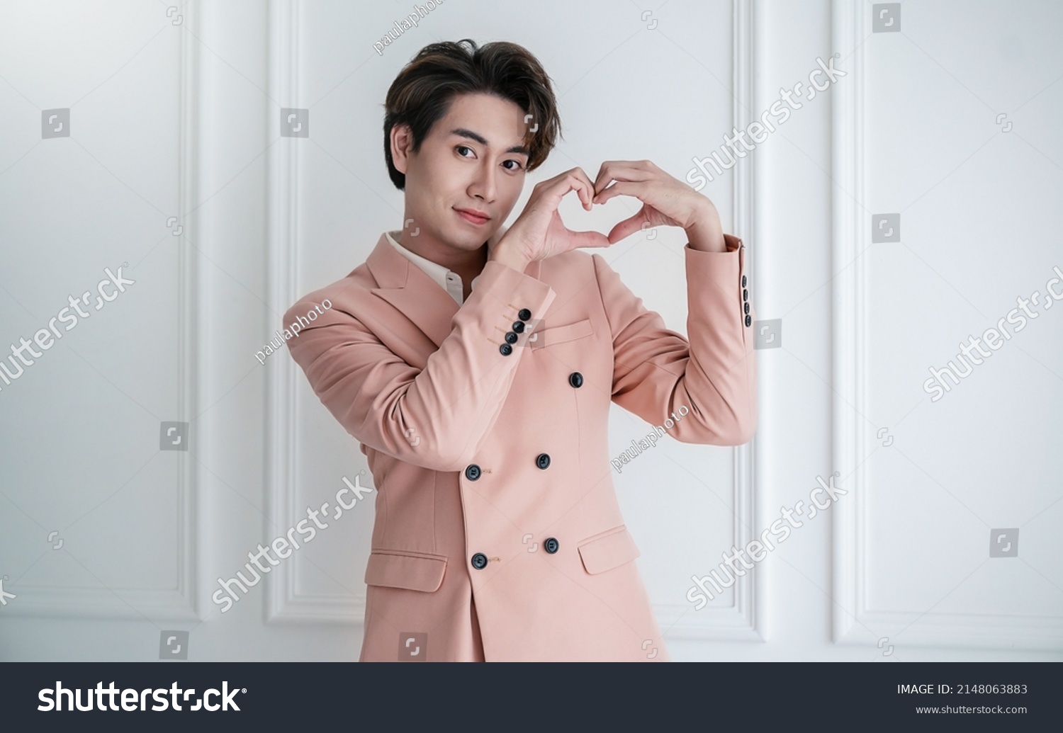 Portrait of young handsome smile asian business man in pink suit hands gesture in heart shape. Smile face asian guy model. Japanese or korean boy lifestyle, happy man valentines day, love concept #2148063883